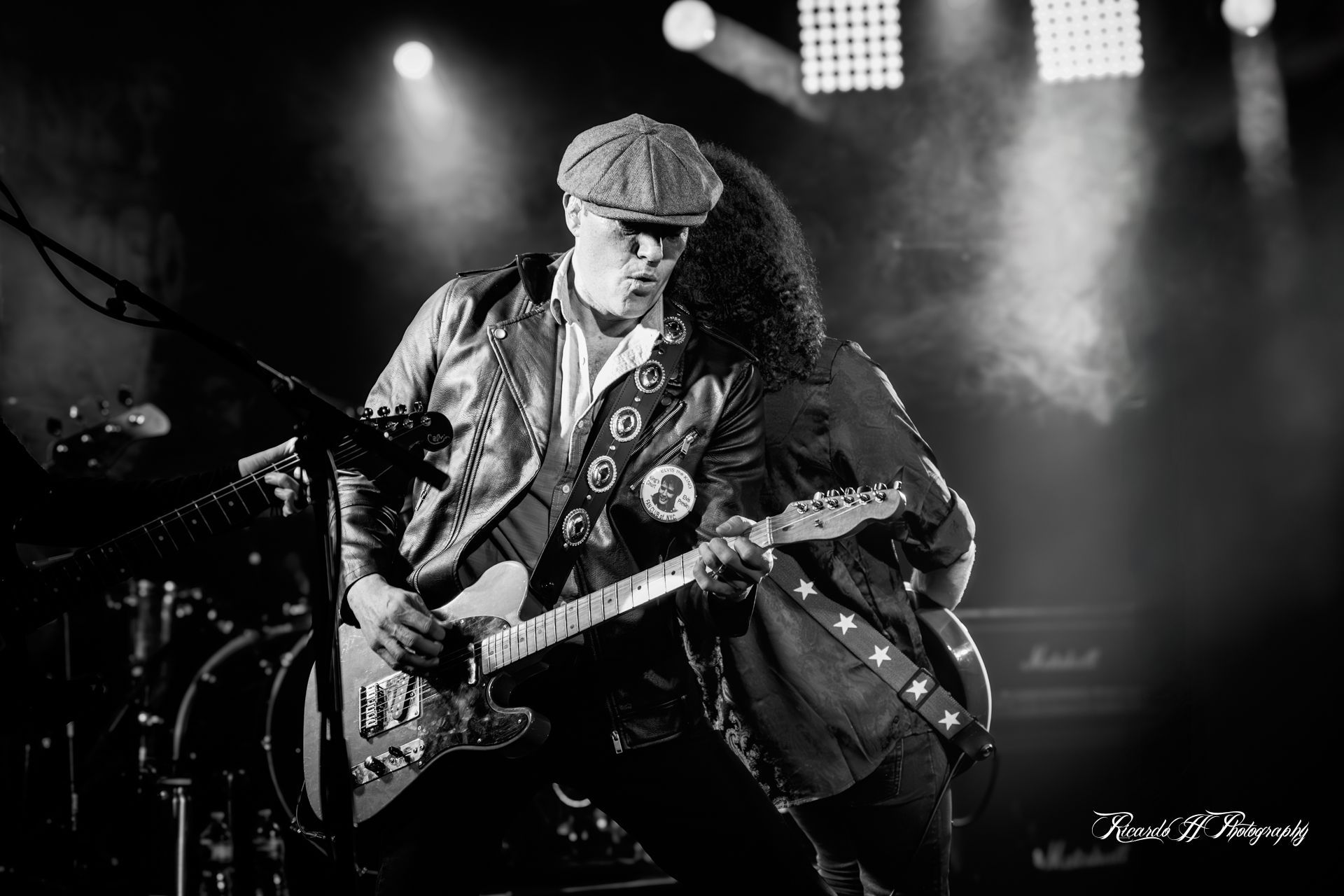A man is playing a guitar on a stage in a black and white photo.