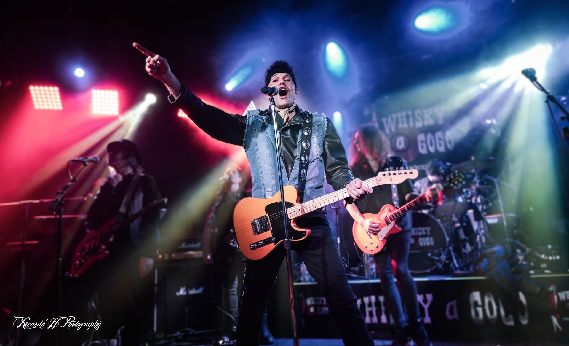 A man is playing a guitar and singing into a microphone on a stage.