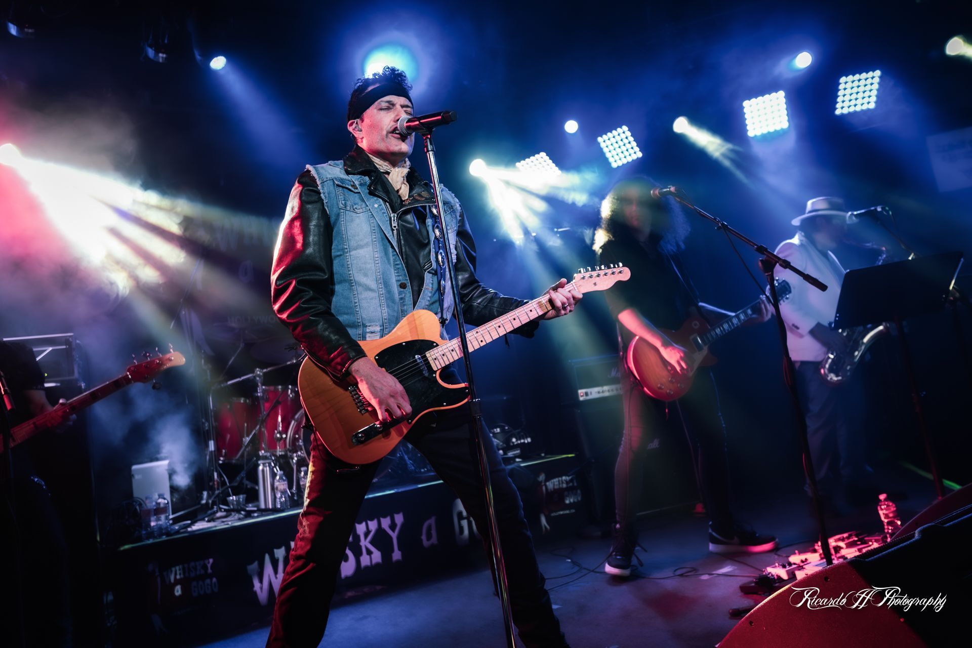 A man is playing a guitar and singing into a microphone on a stage.