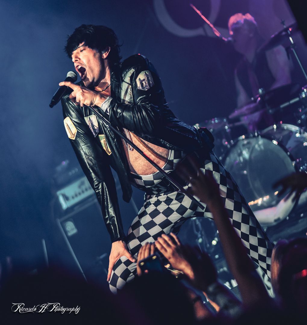 A man singing into a microphone in front of a crowd