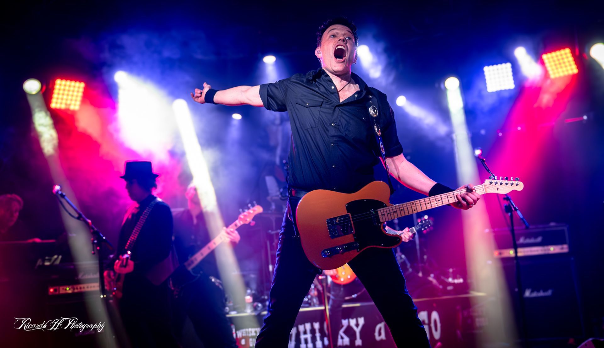 A man is playing a guitar on a stage in front of a crowd.