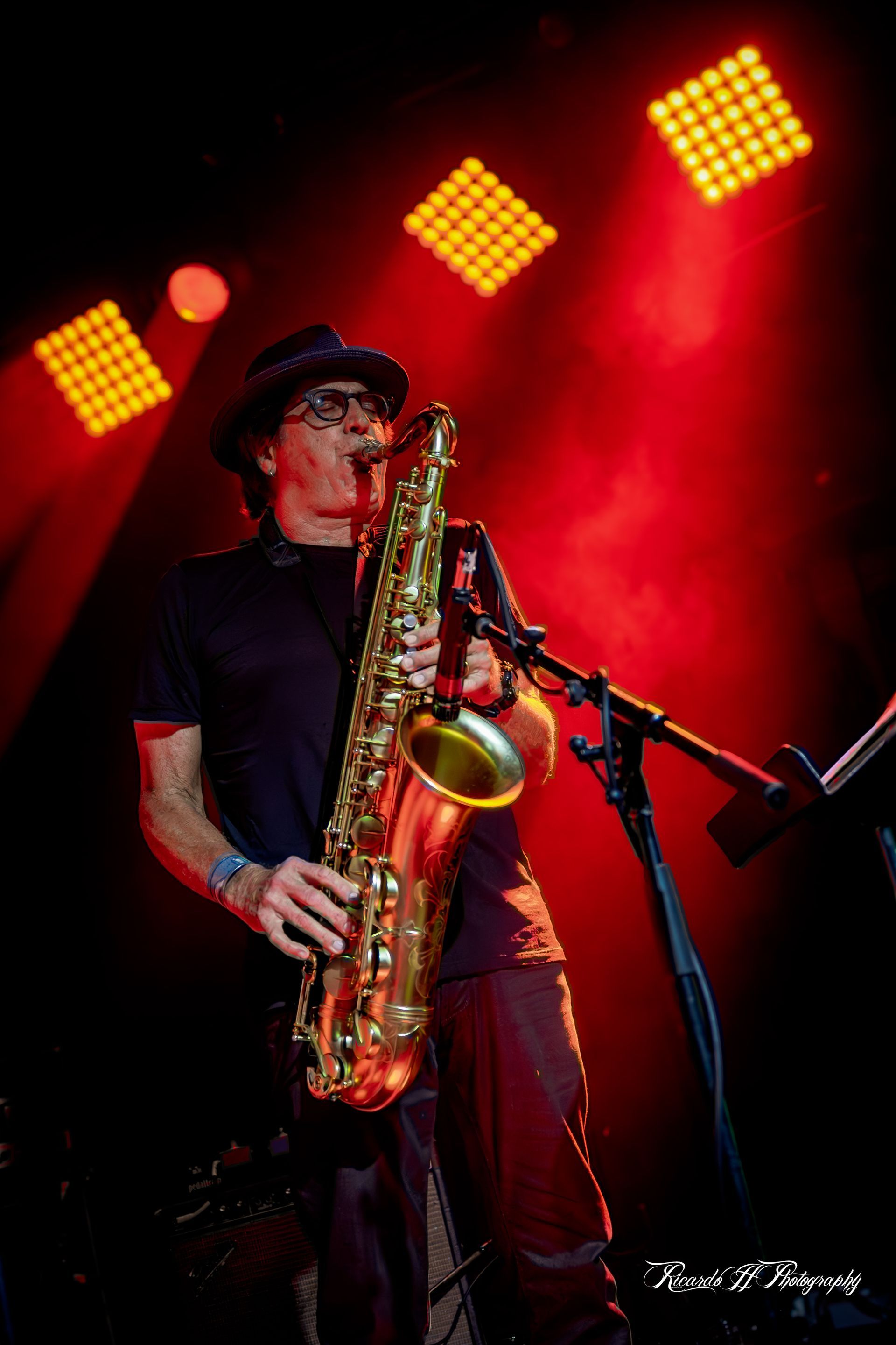 A man is playing a saxophone on a stage in front of a microphone.