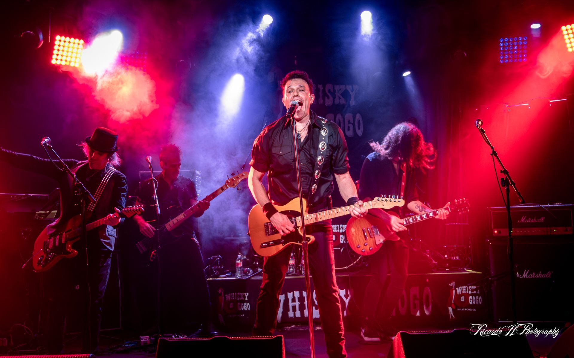 A man is playing a guitar and singing into a microphone on a stage.