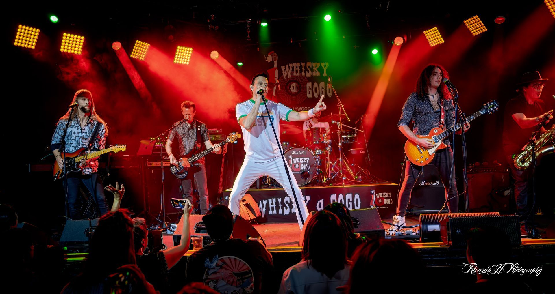A group of men are playing instruments on a stage in front of a crowd.