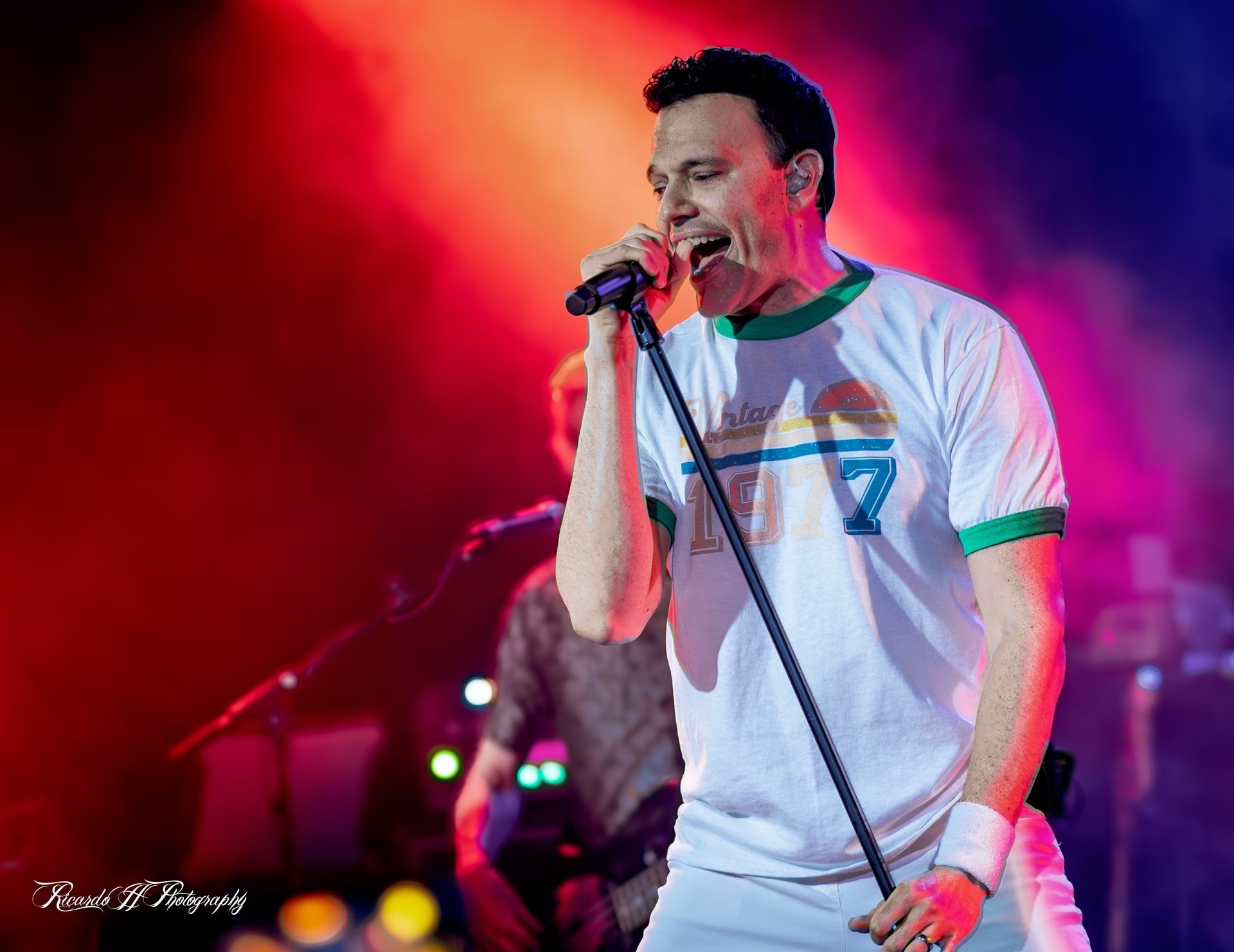 A man is singing into a microphone on a stage.