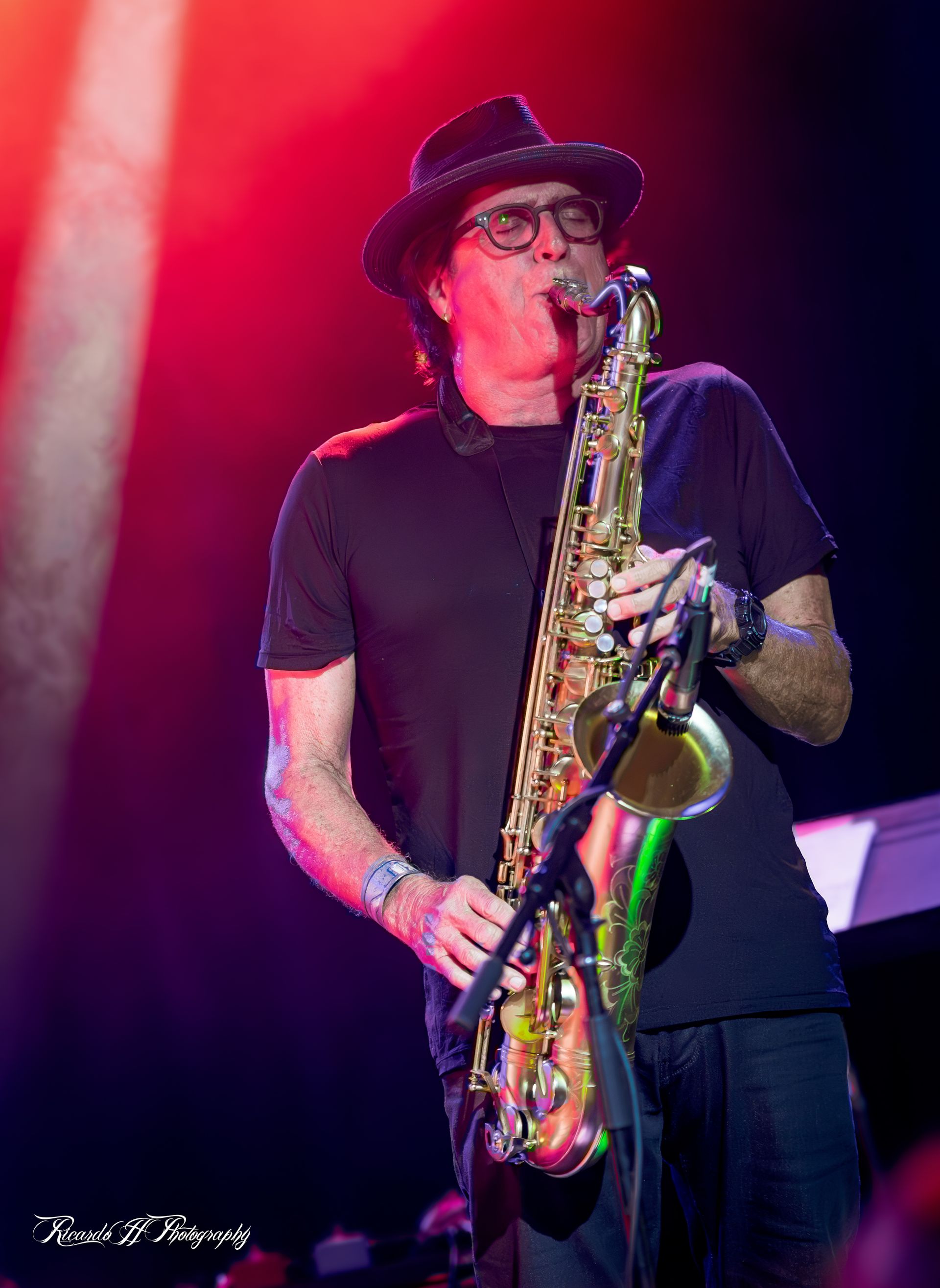 A man in a hat is playing a saxophone on a stage.