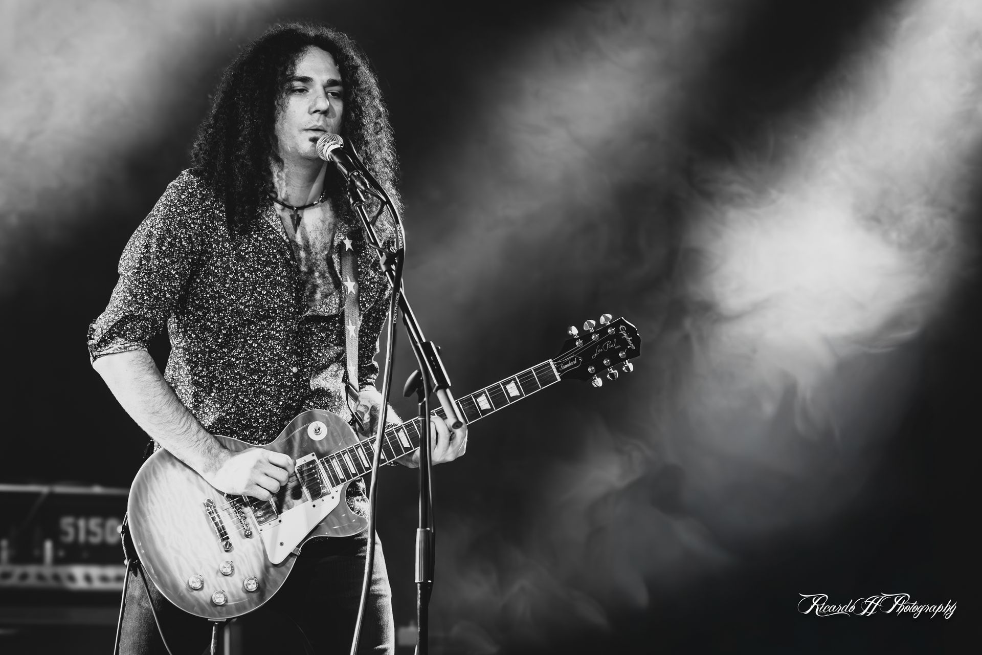 A man with long hair is playing a guitar and singing into a microphone.