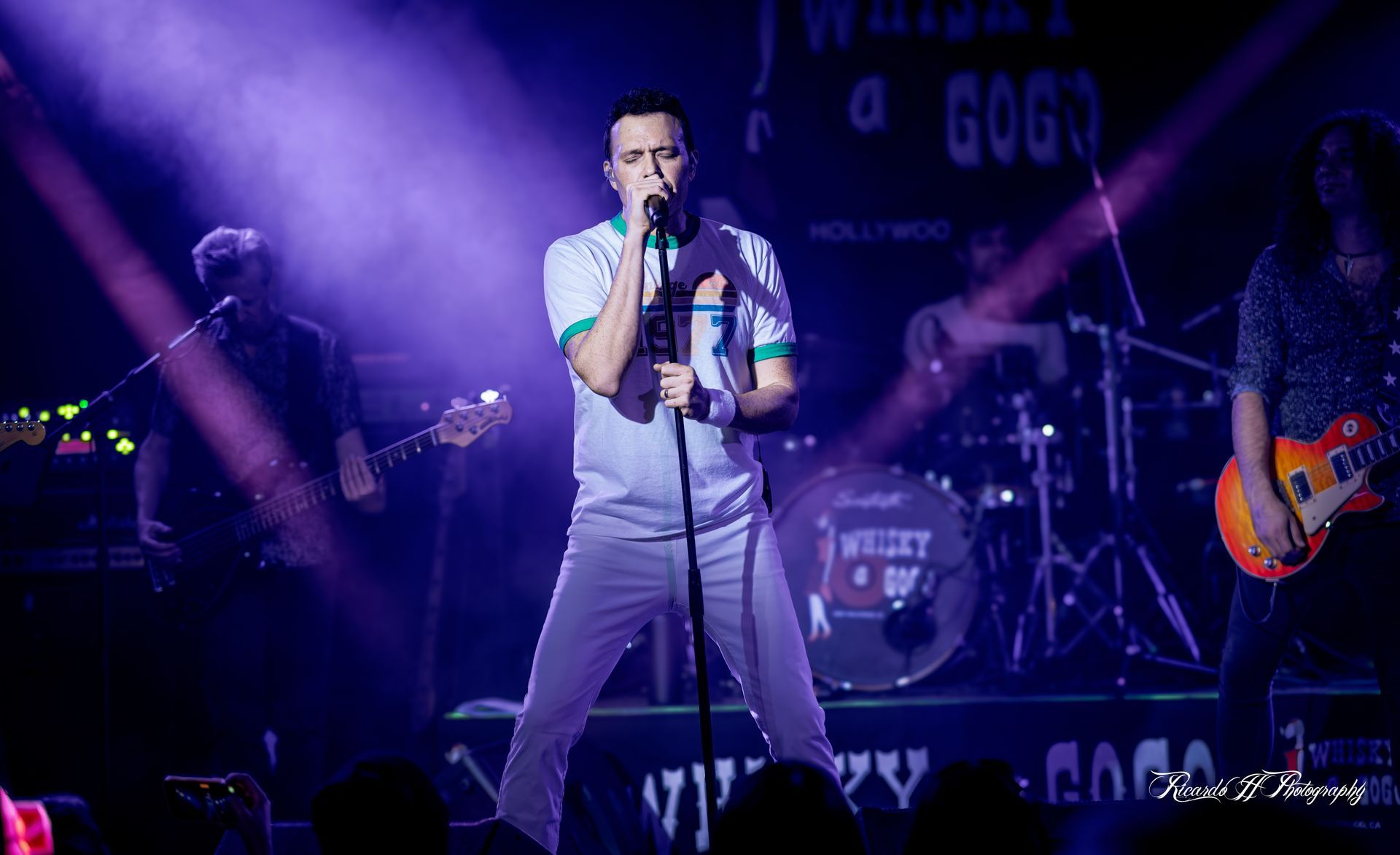 A man is singing into a microphone on a stage in front of a crowd.