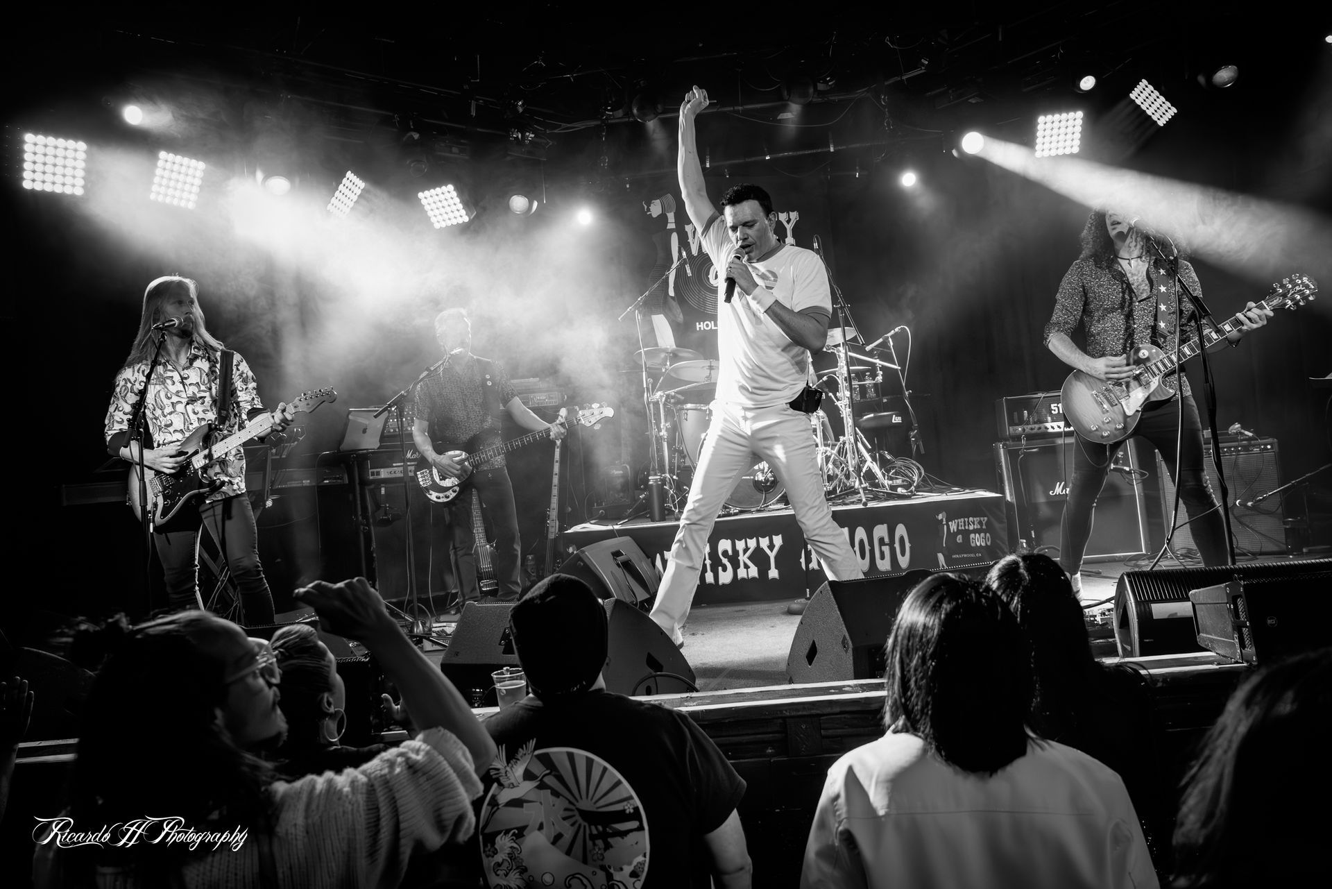 A black and white photo of a band performing on stage