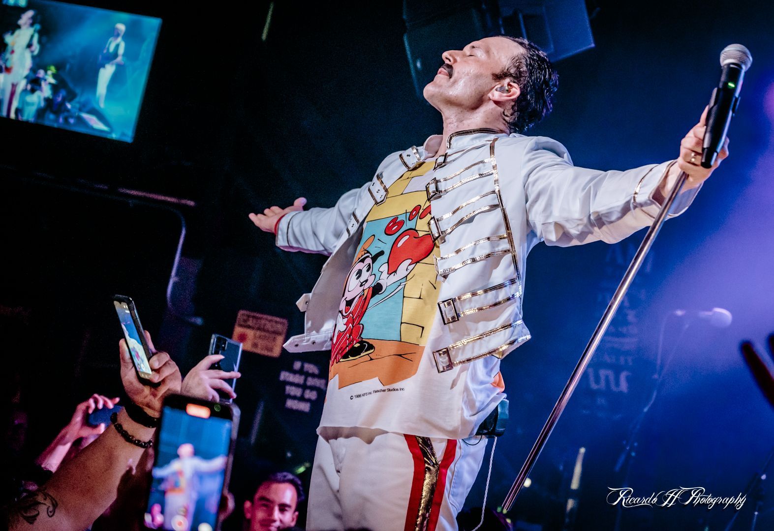A man is singing into a microphone on a stage in front of a crowd.