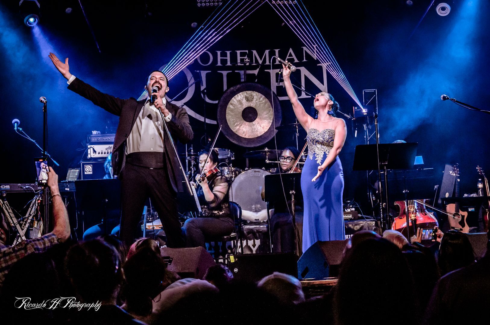 A man and a woman are singing on stage in front of a crowd.
