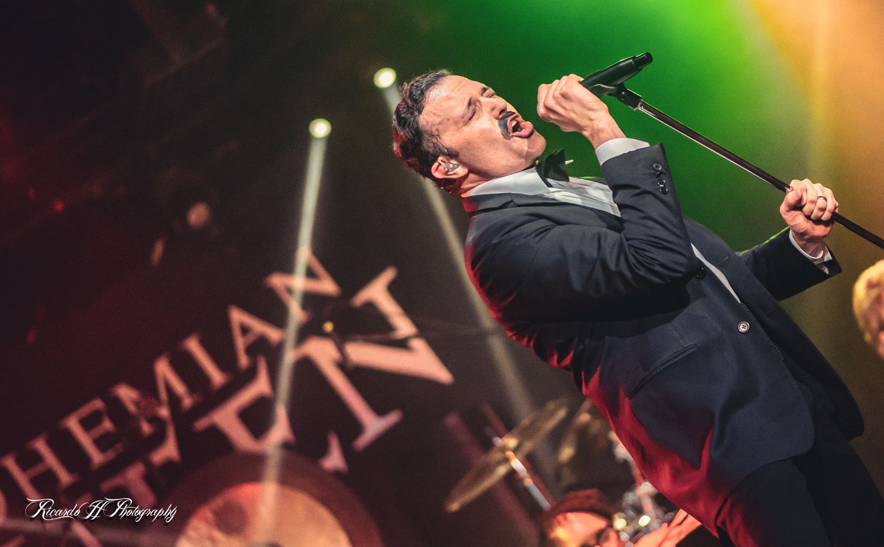 A man in a suit is singing into a microphone on a stage.