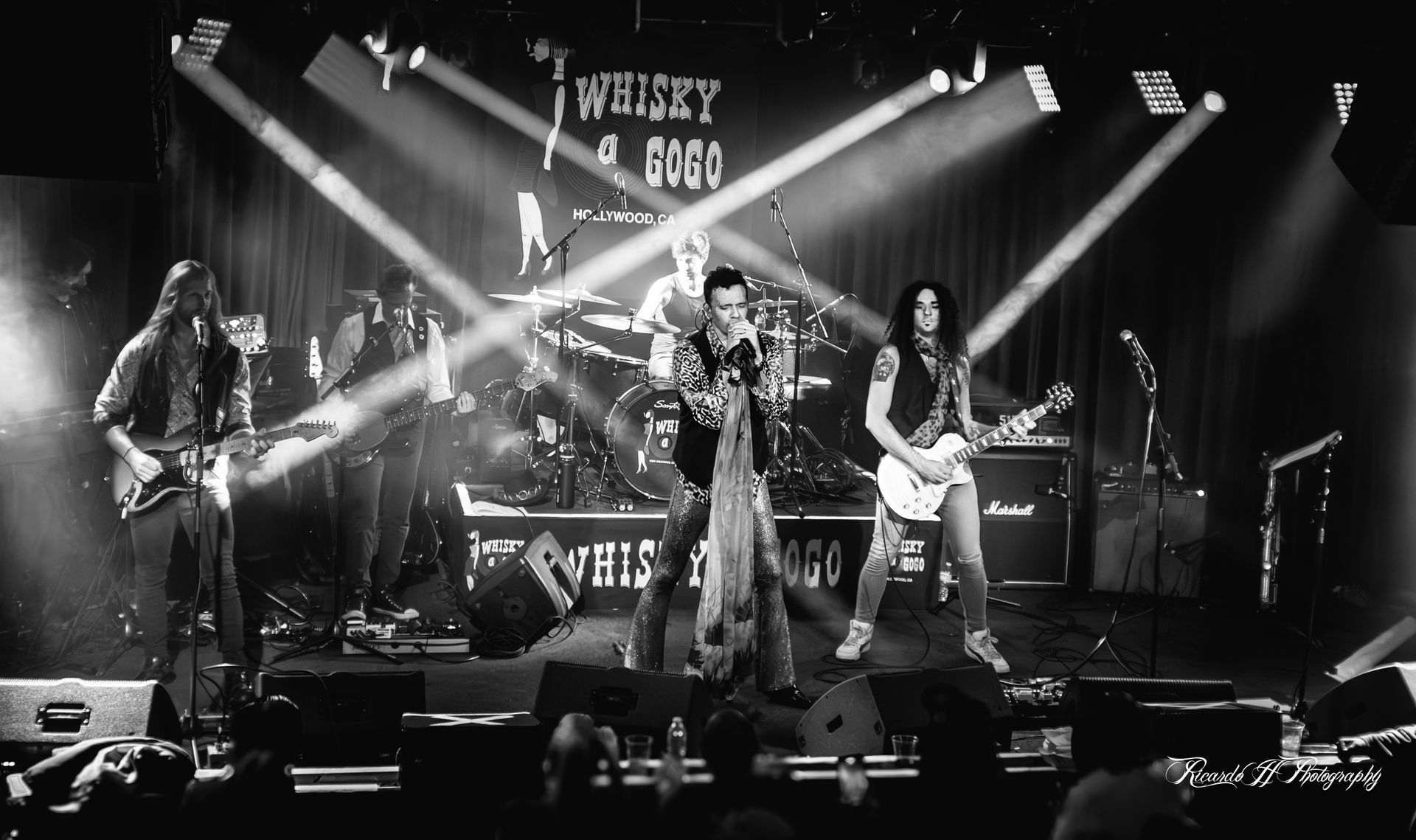 A black and white photo of a band performing on stage