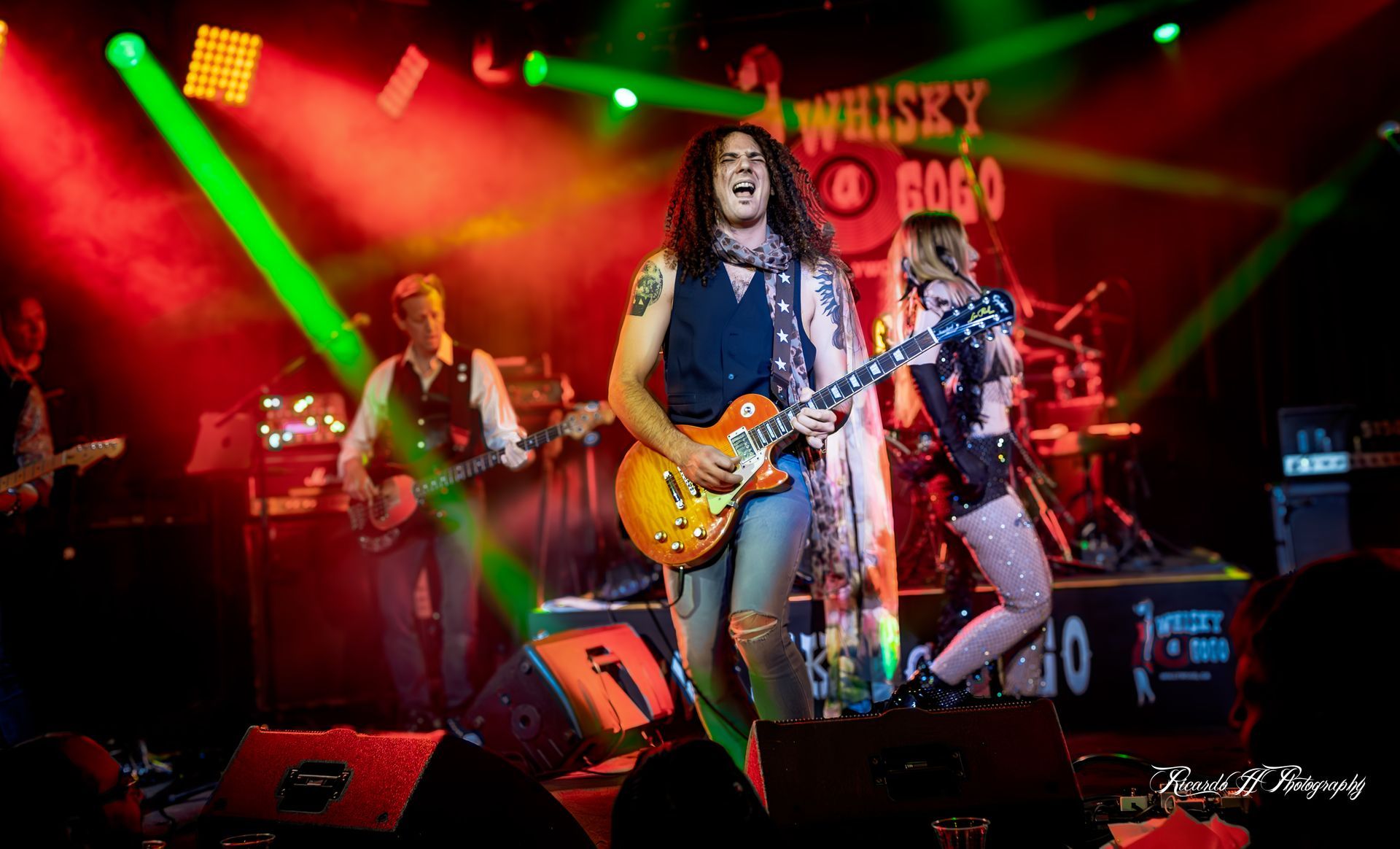 A man is playing a guitar on stage in front of a crowd.