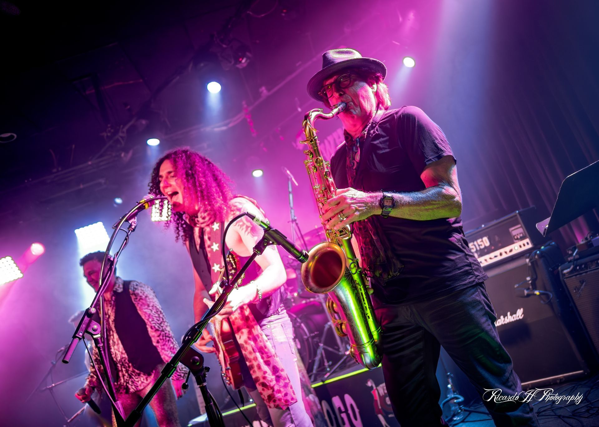A man is playing a saxophone and a woman is singing into a microphone on a stage.