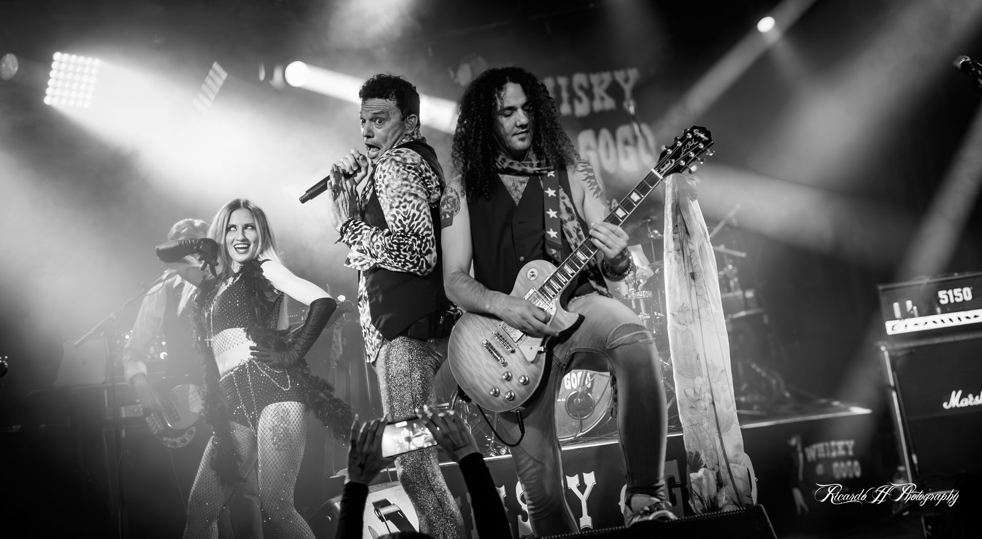 A black and white photo of a group of people playing instruments on a stage.