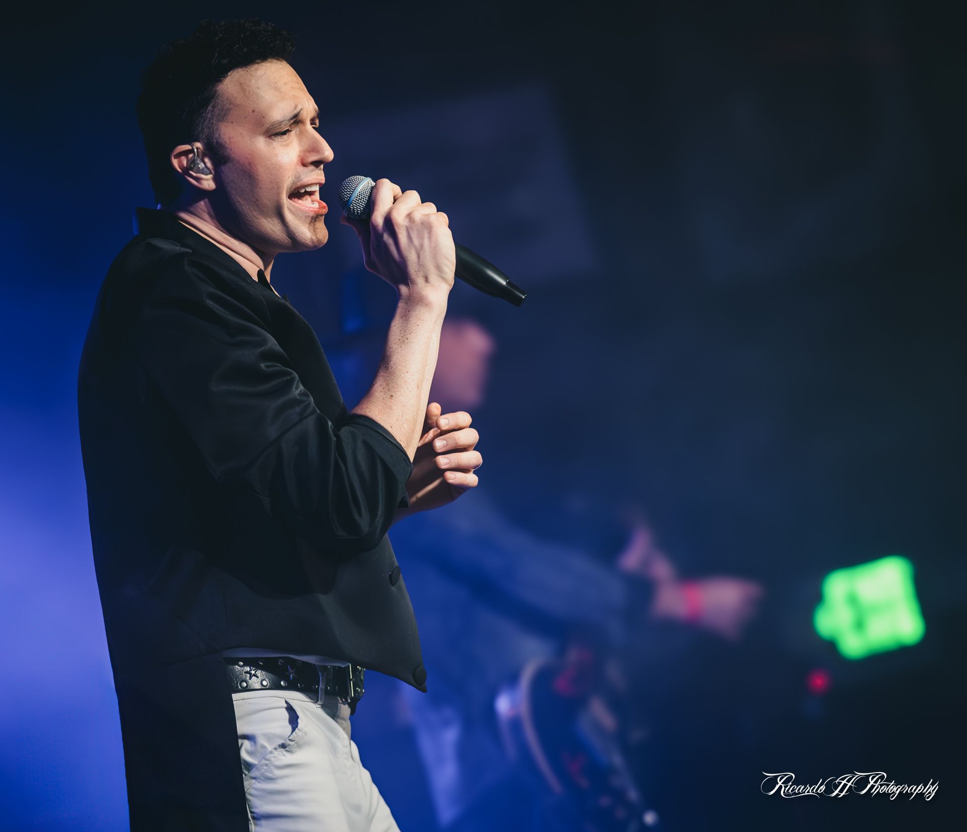 A man is singing into a microphone on a stage