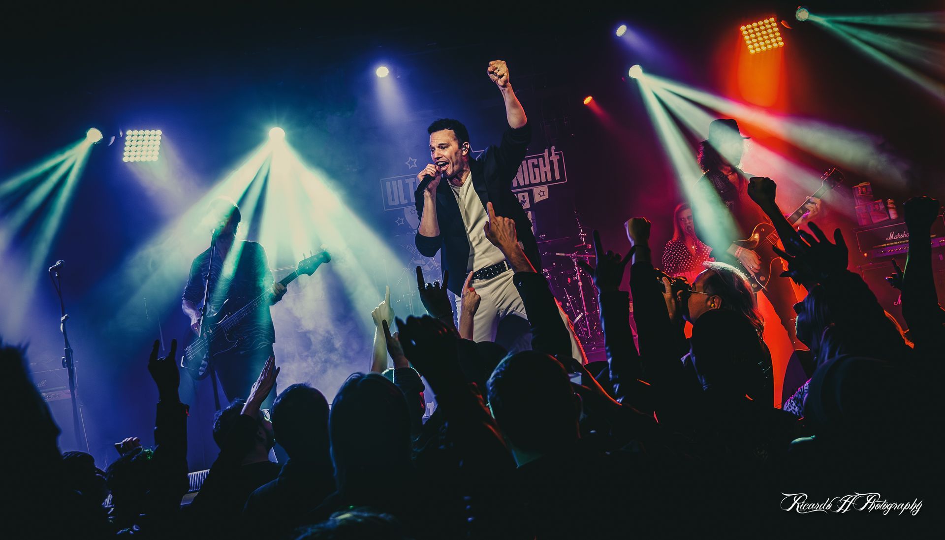 A man is singing into a microphone on a stage in front of a crowd.