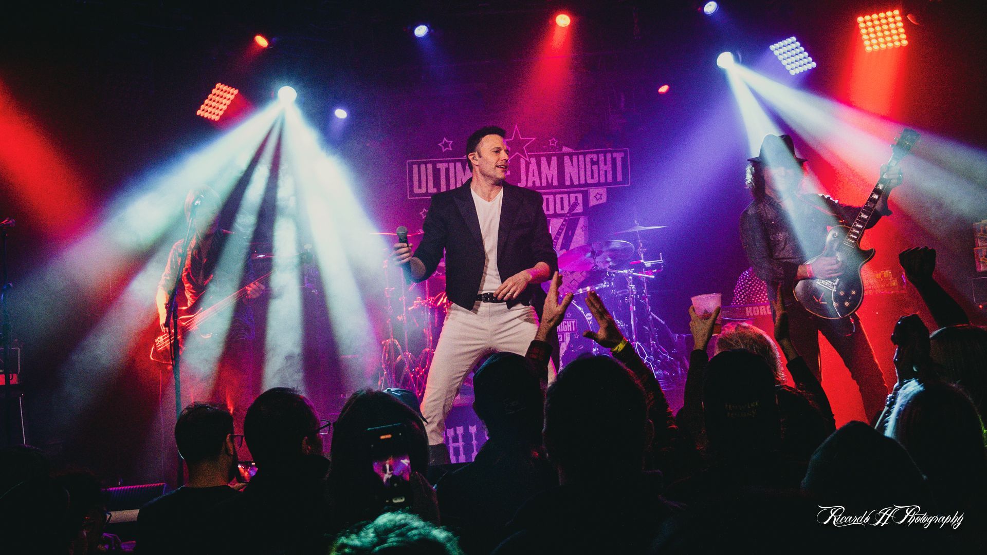 A man is singing into a microphone on a stage in front of a crowd.