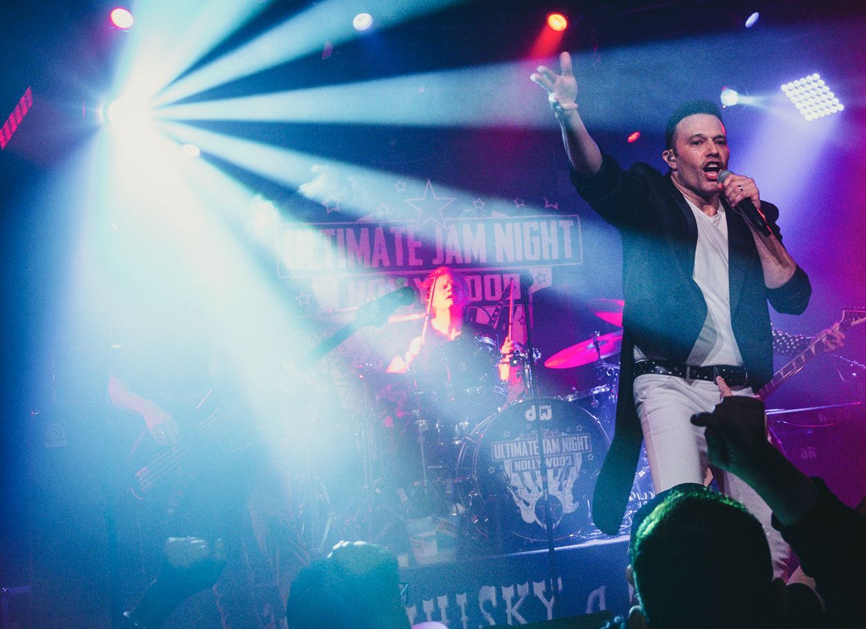 A man is singing into a microphone on a stage in front of a crowd.