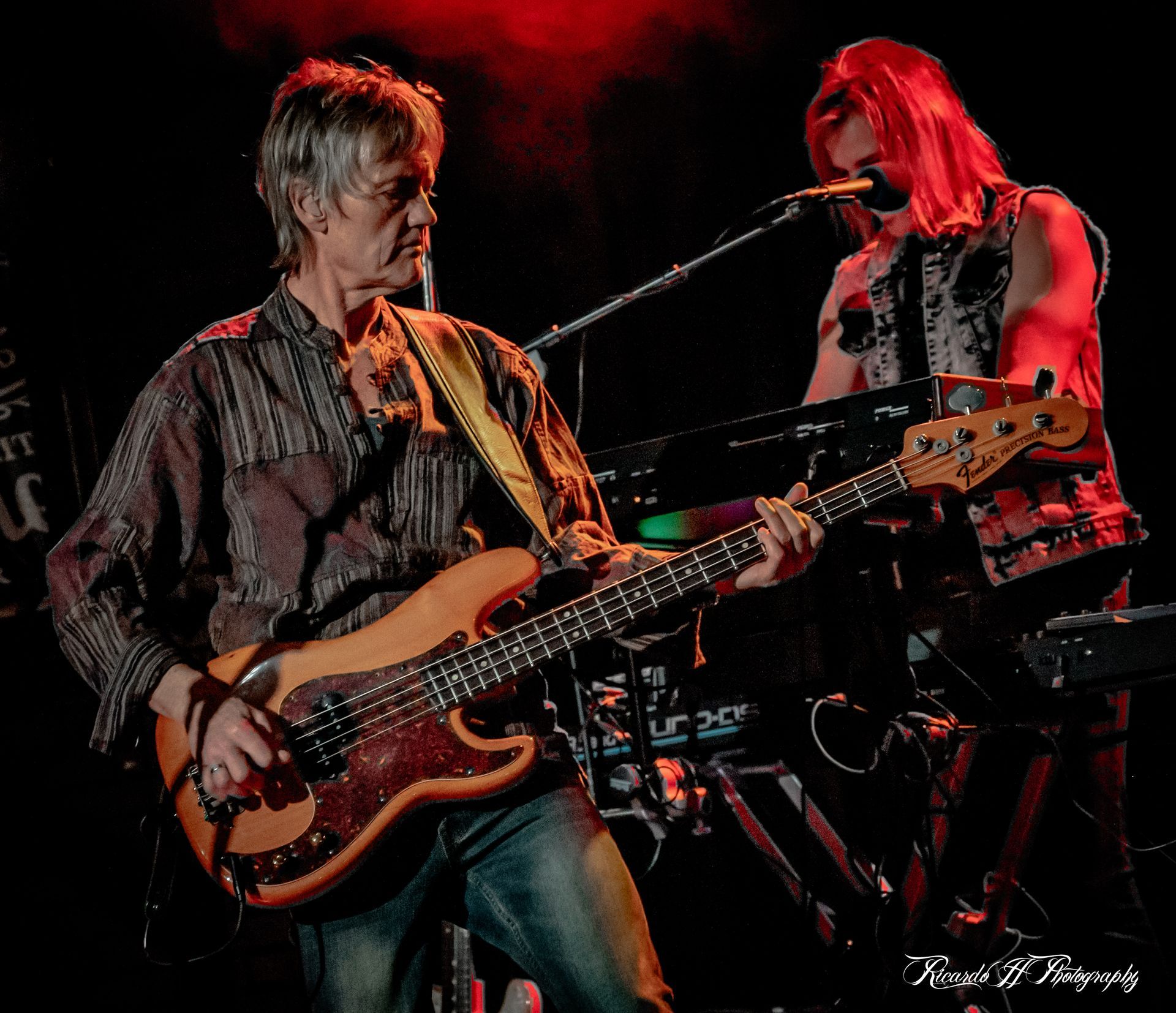 A man playing a bass guitar next to another man singing into a microphone