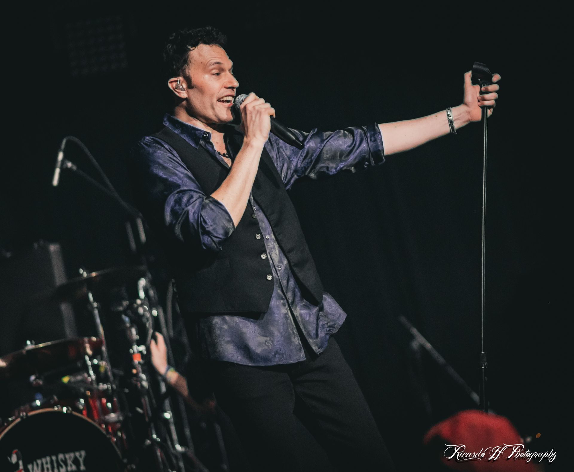 A man is singing into a microphone on a stage.