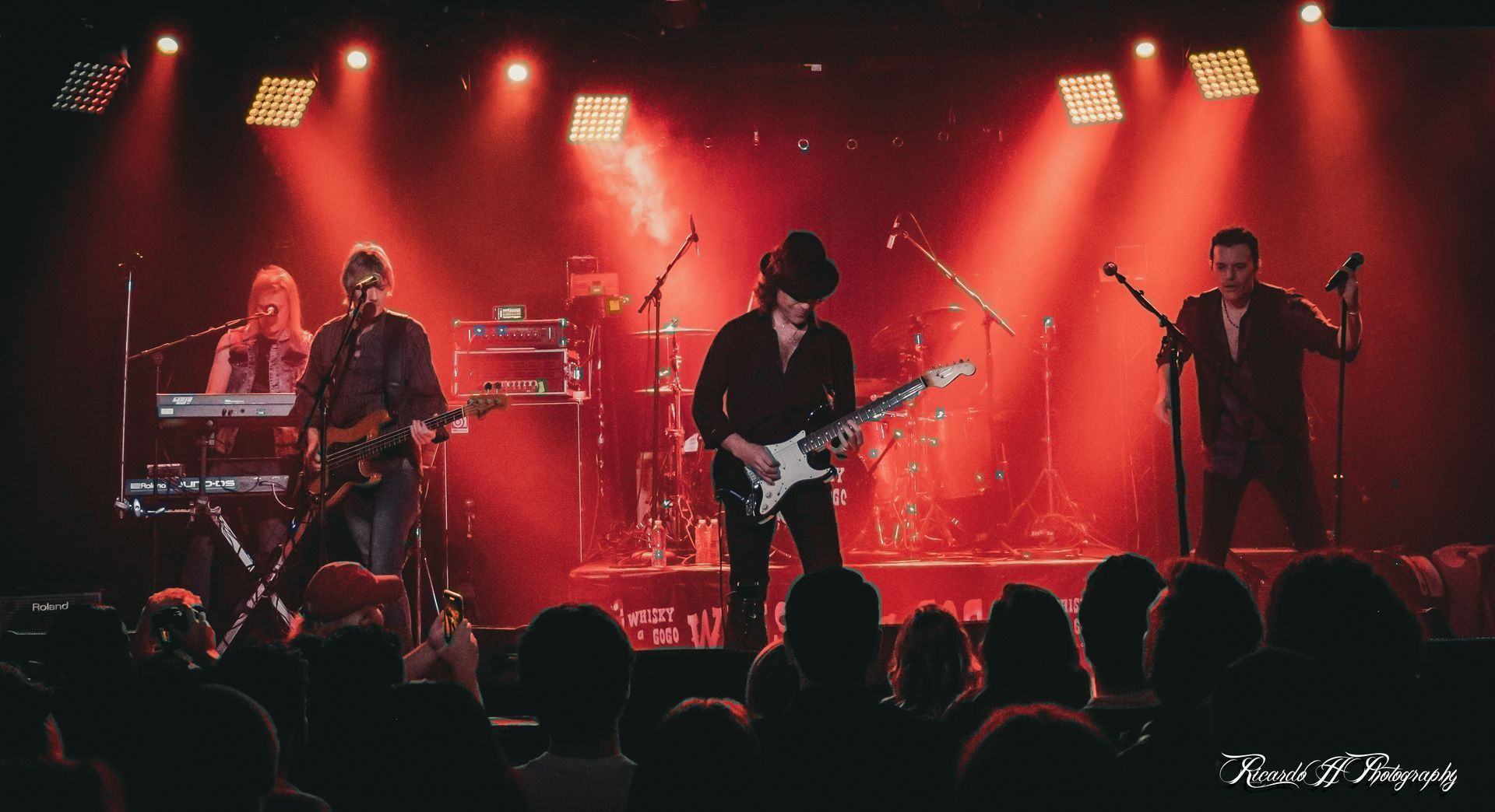 A group of people are playing instruments on a stage in front of a crowd.