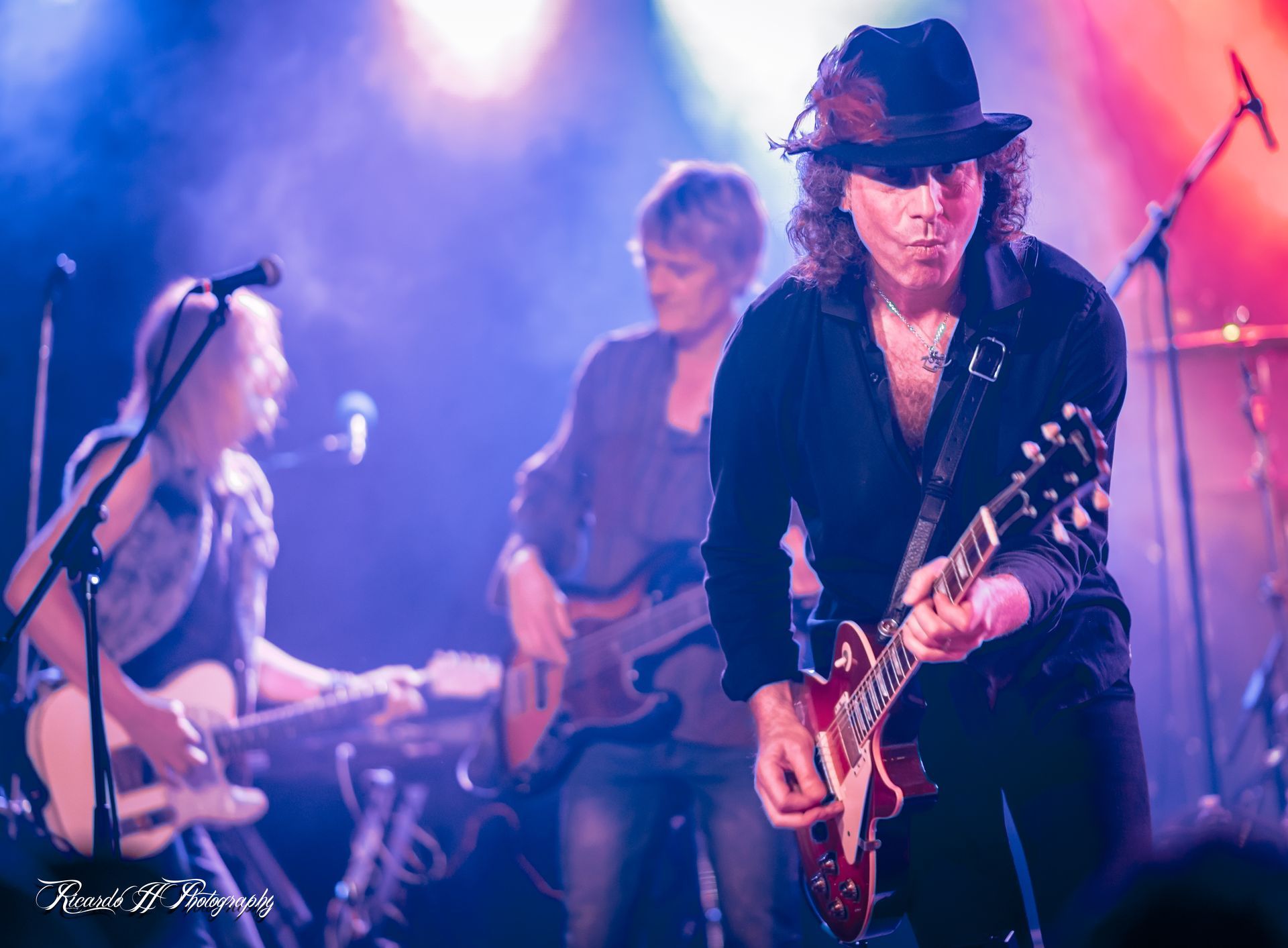 A man in a hat is playing a guitar on a stage.