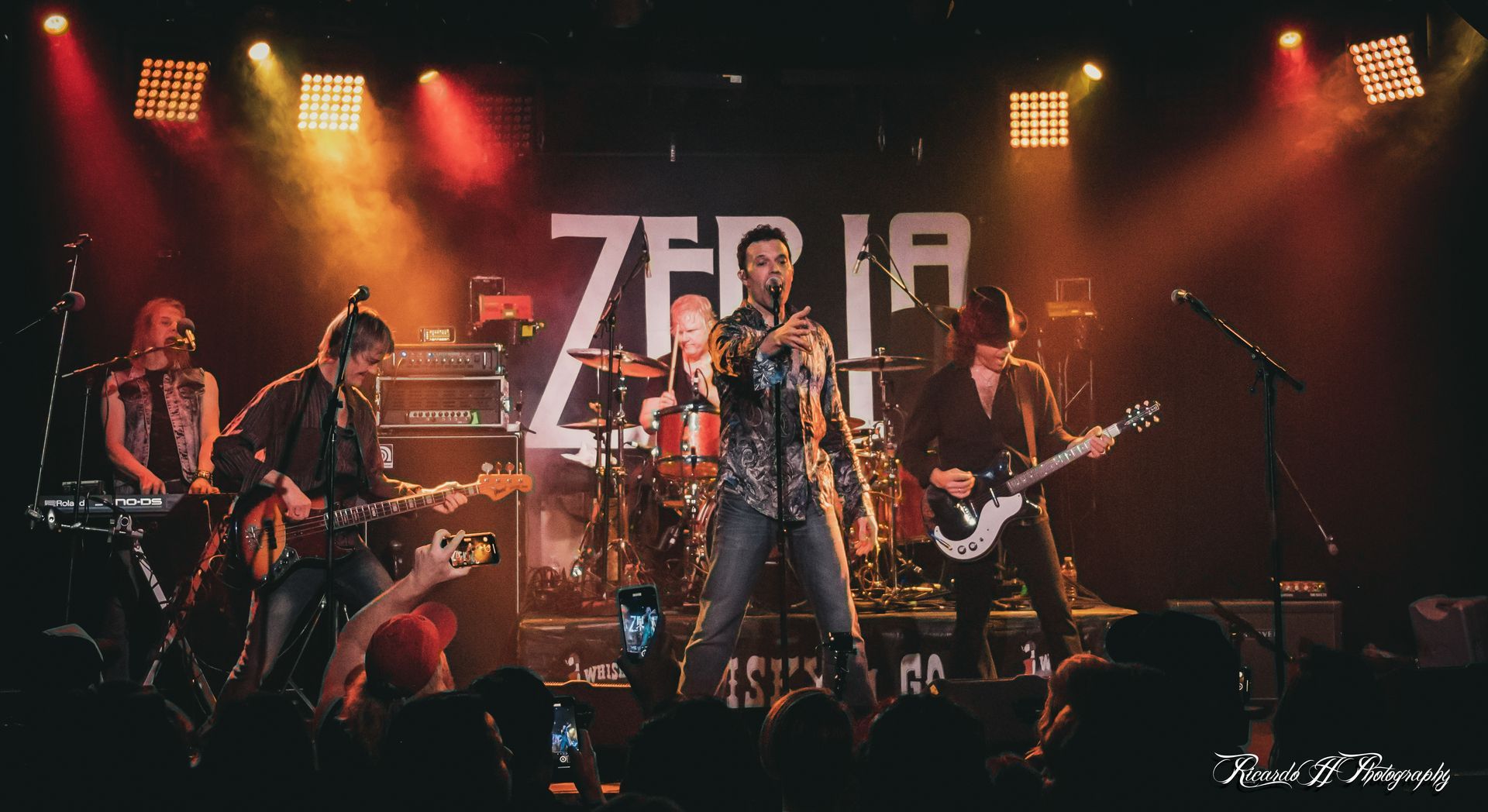 A group of people are playing instruments on a stage in front of a crowd.