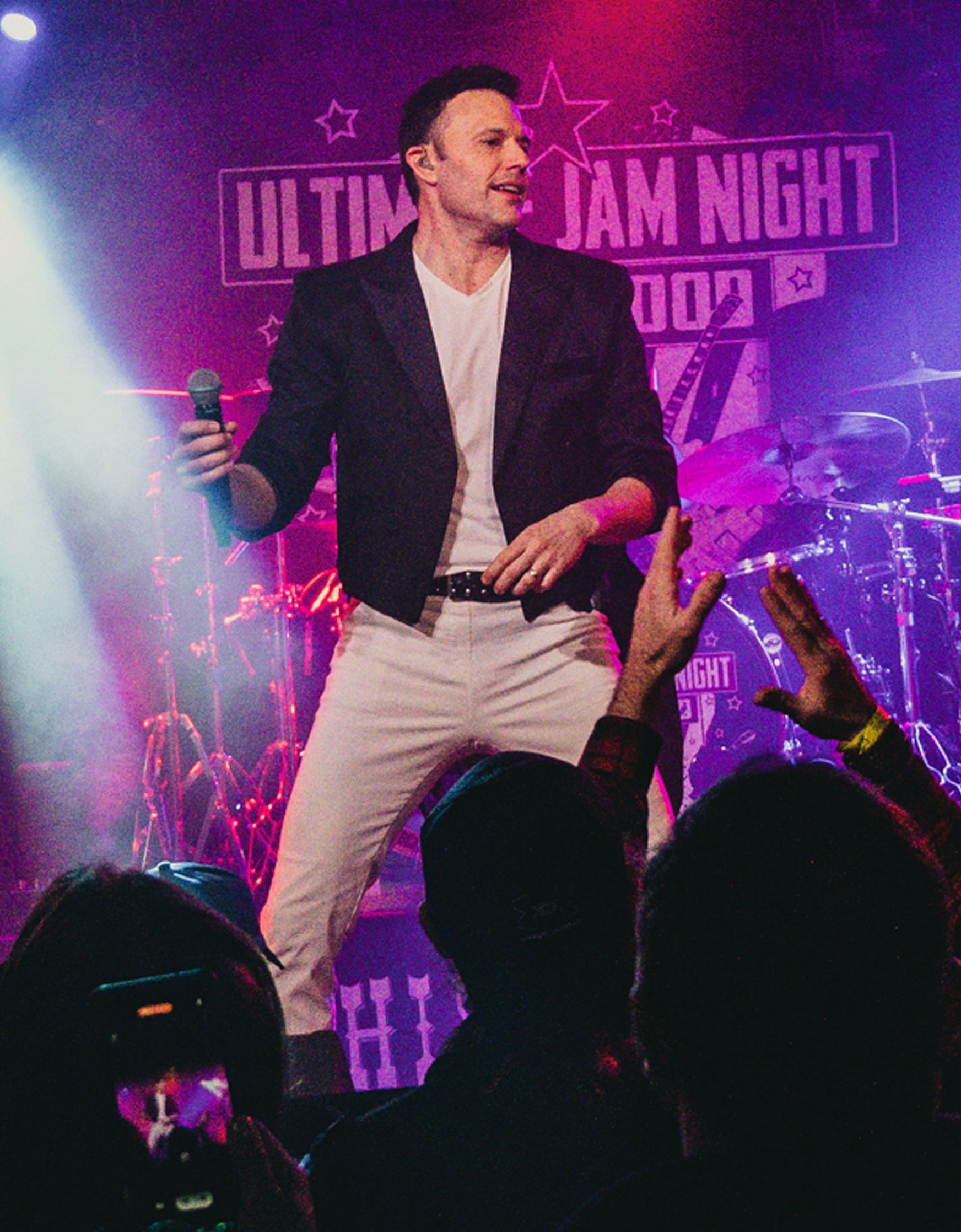 A man is singing into a microphone on a stage in front of a crowd.