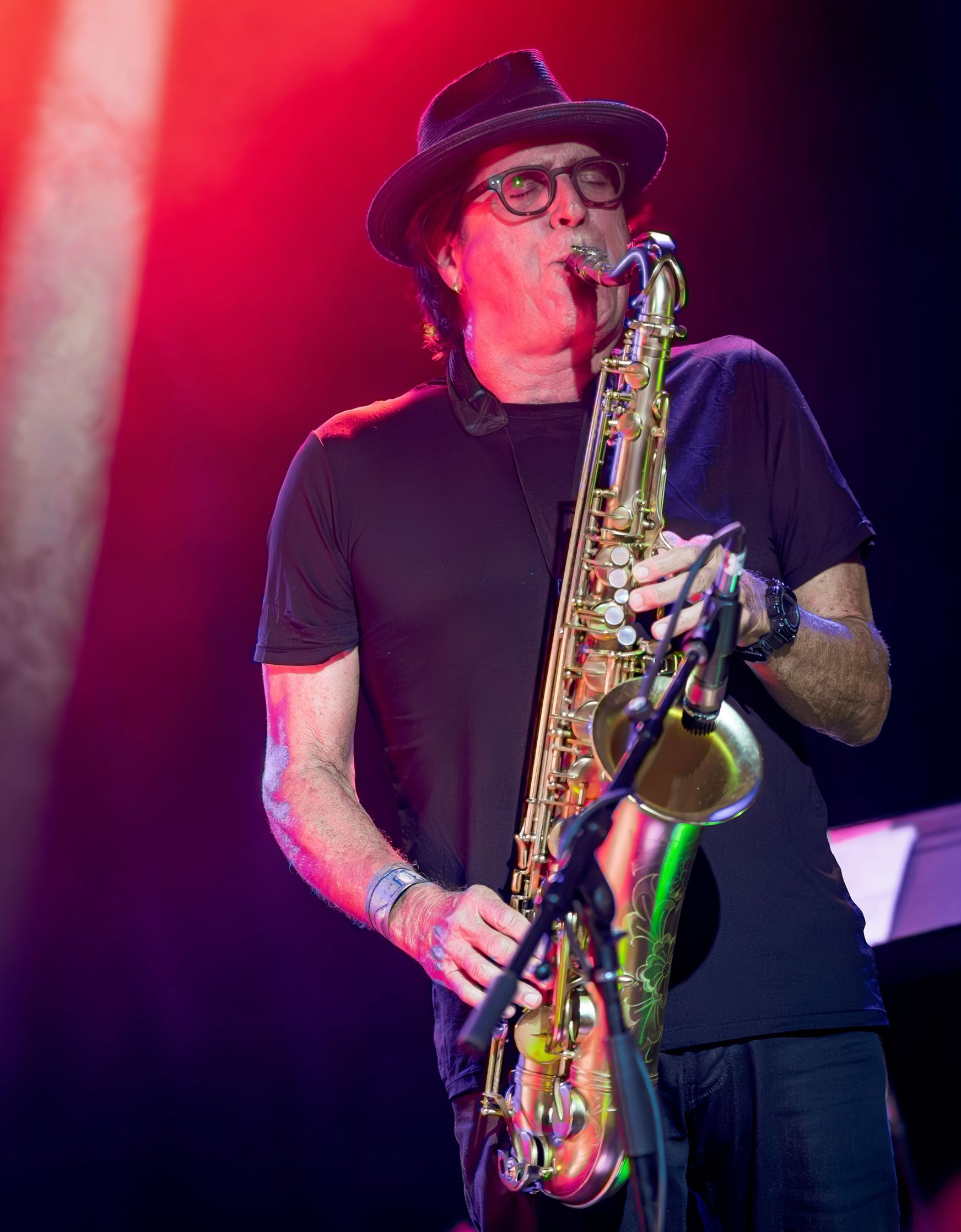 A man in a hat is playing a saxophone on a stage.