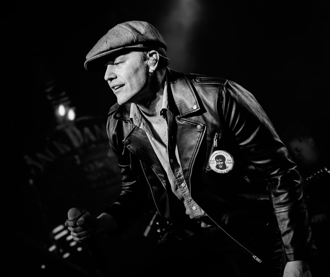 A man is singing into a microphone in a black and white photo.