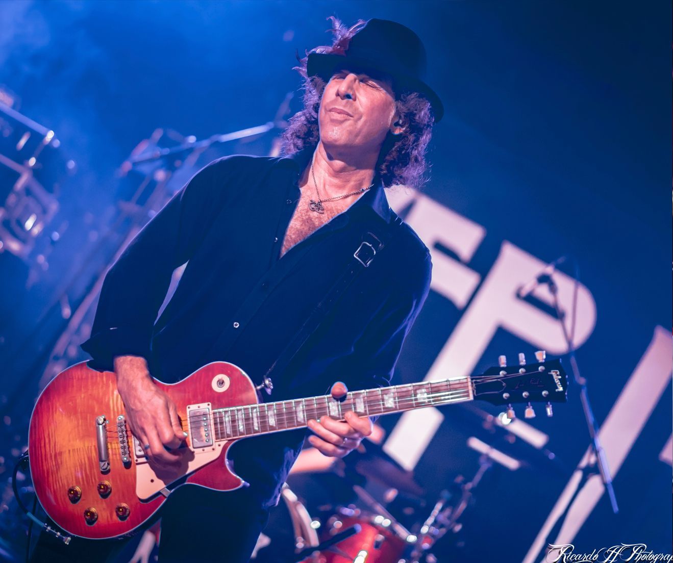 A man in a hat is playing a guitar on stage