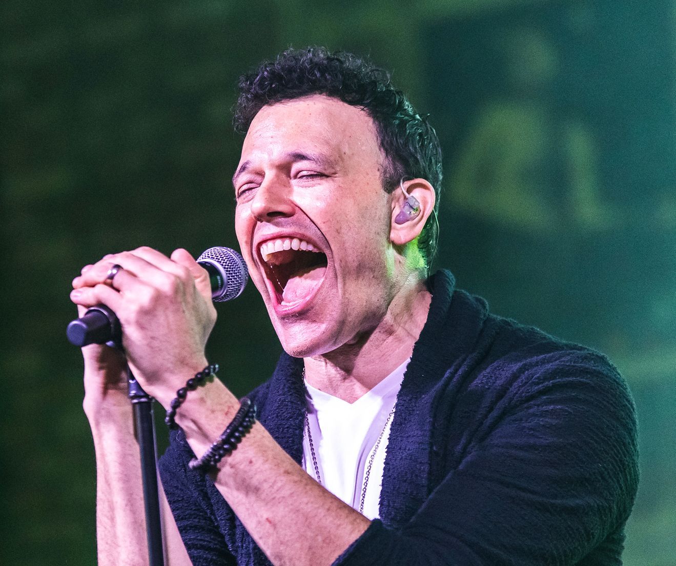 A man is singing into a microphone with his mouth open.