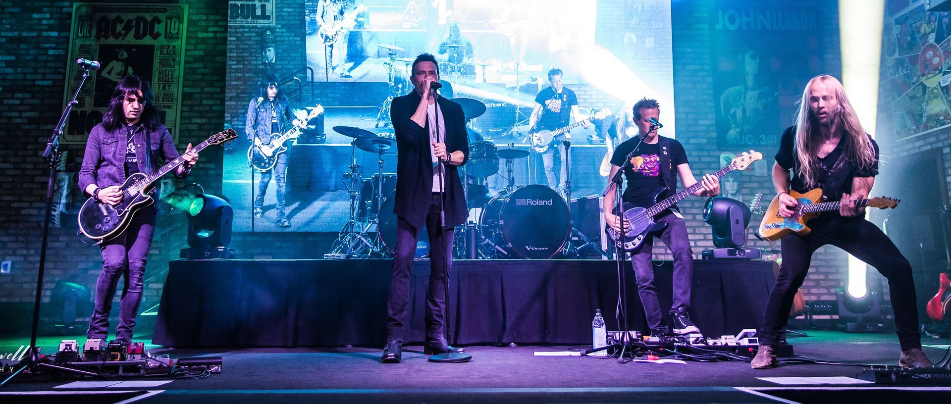 A group of men are standing on a stage playing guitars and singing into microphones.