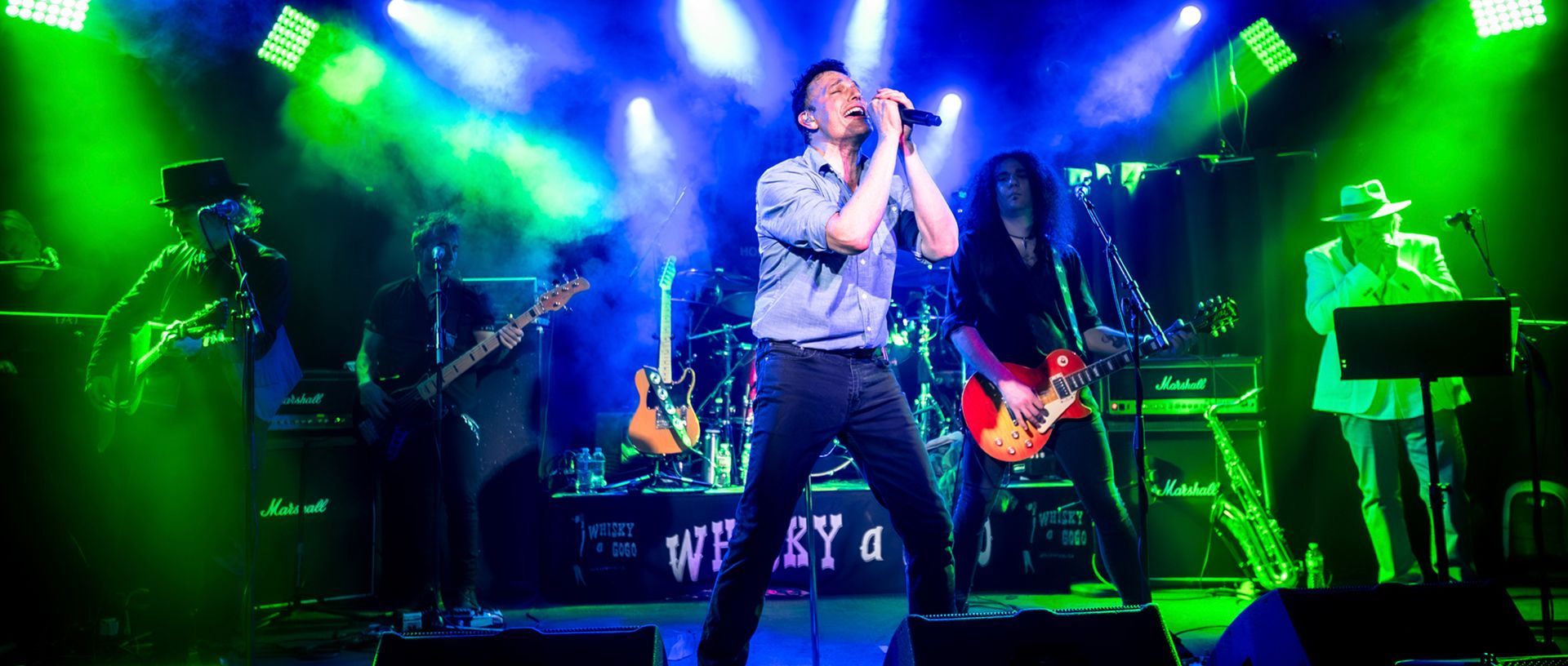 A group of people are playing guitars and singing on a stage.