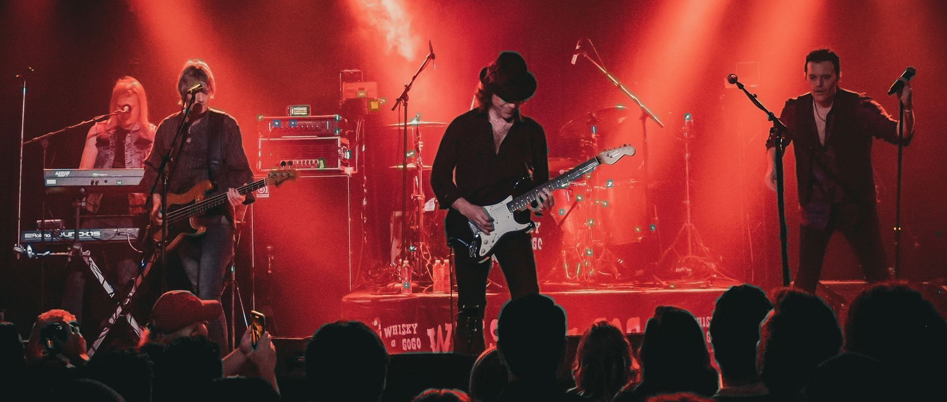 A group of men are playing guitars and singing on a stage in front of a crowd.