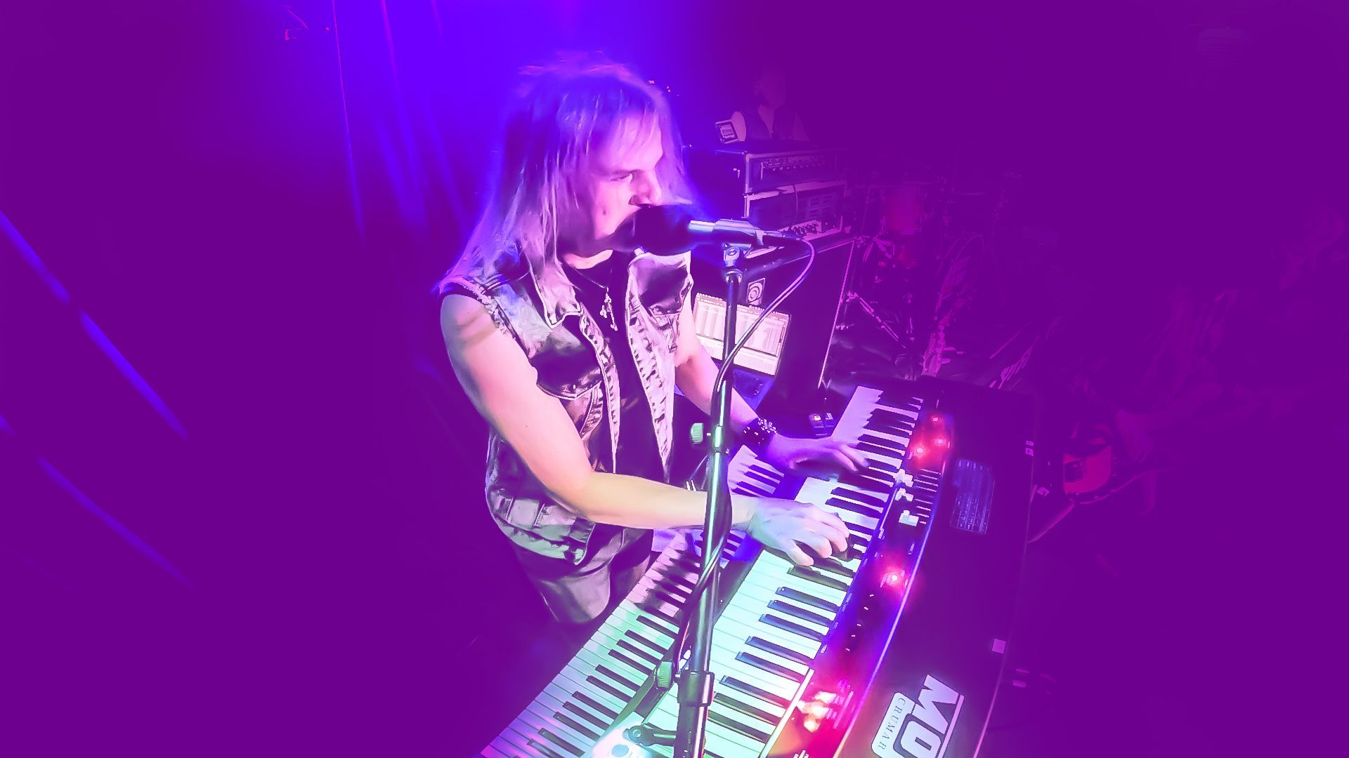 A woman is playing a keyboard and singing into a microphone on a stage.