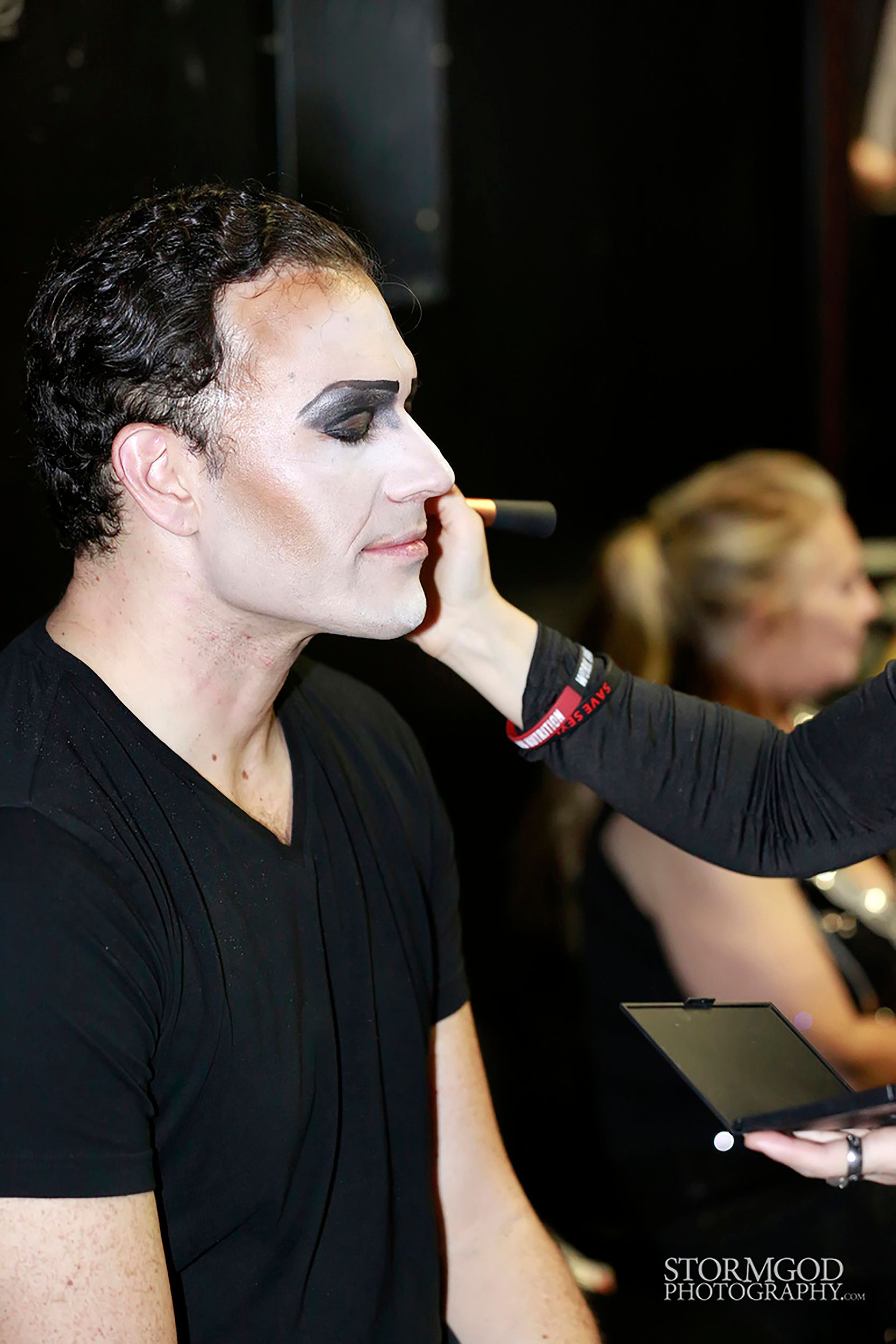 A woman is applying makeup to a man 's face