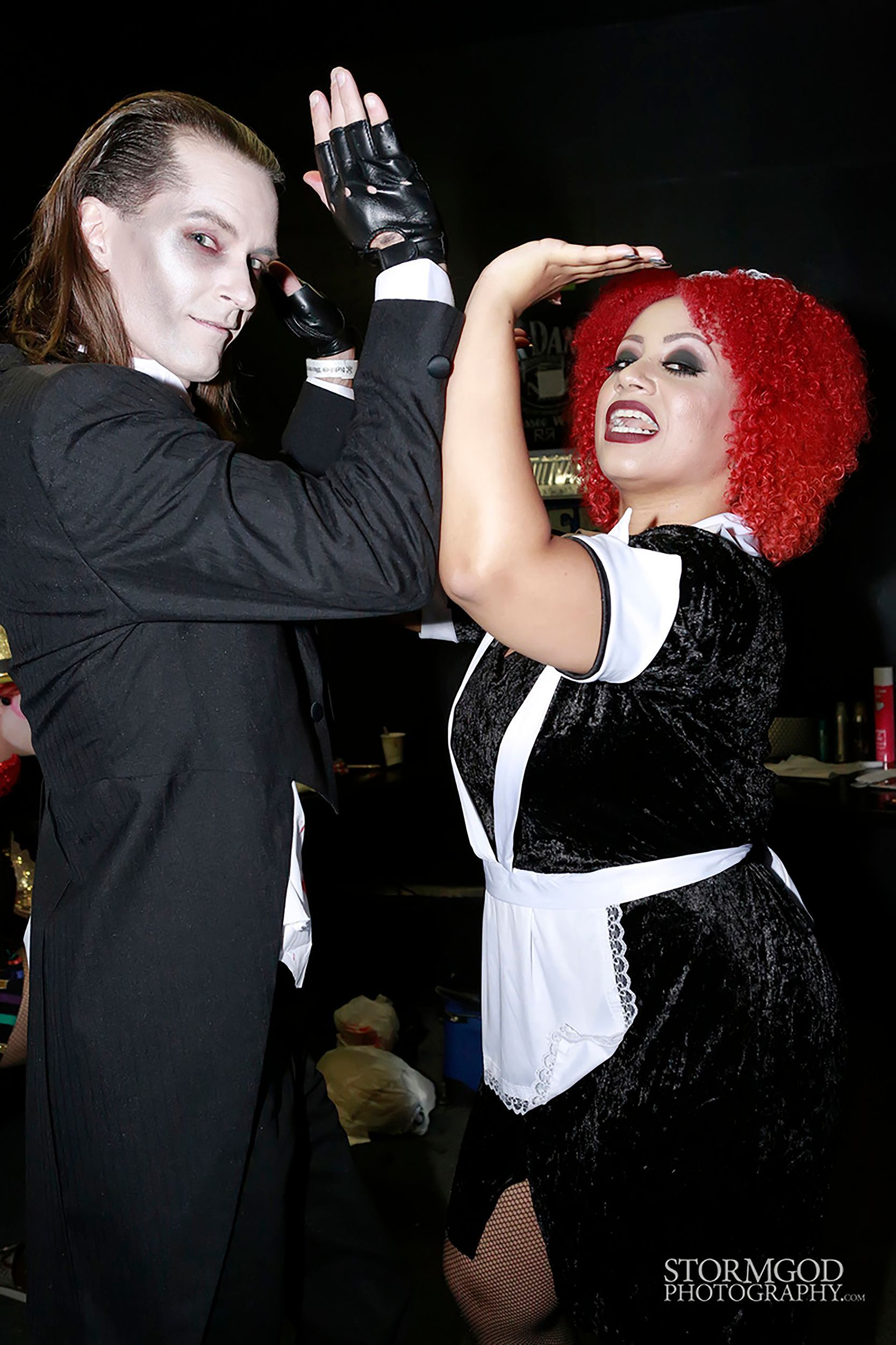 A man dressed as a vampire and a woman dressed as a maid are dancing together
