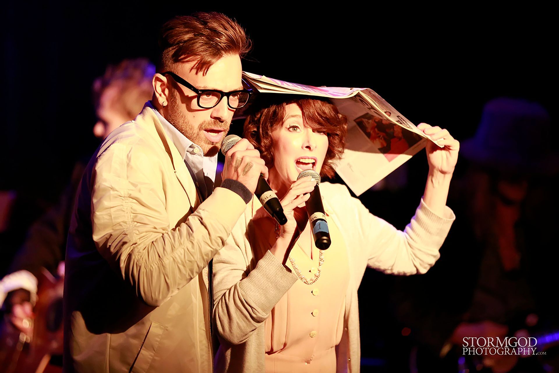 A man and a woman are singing into microphones on a stage.