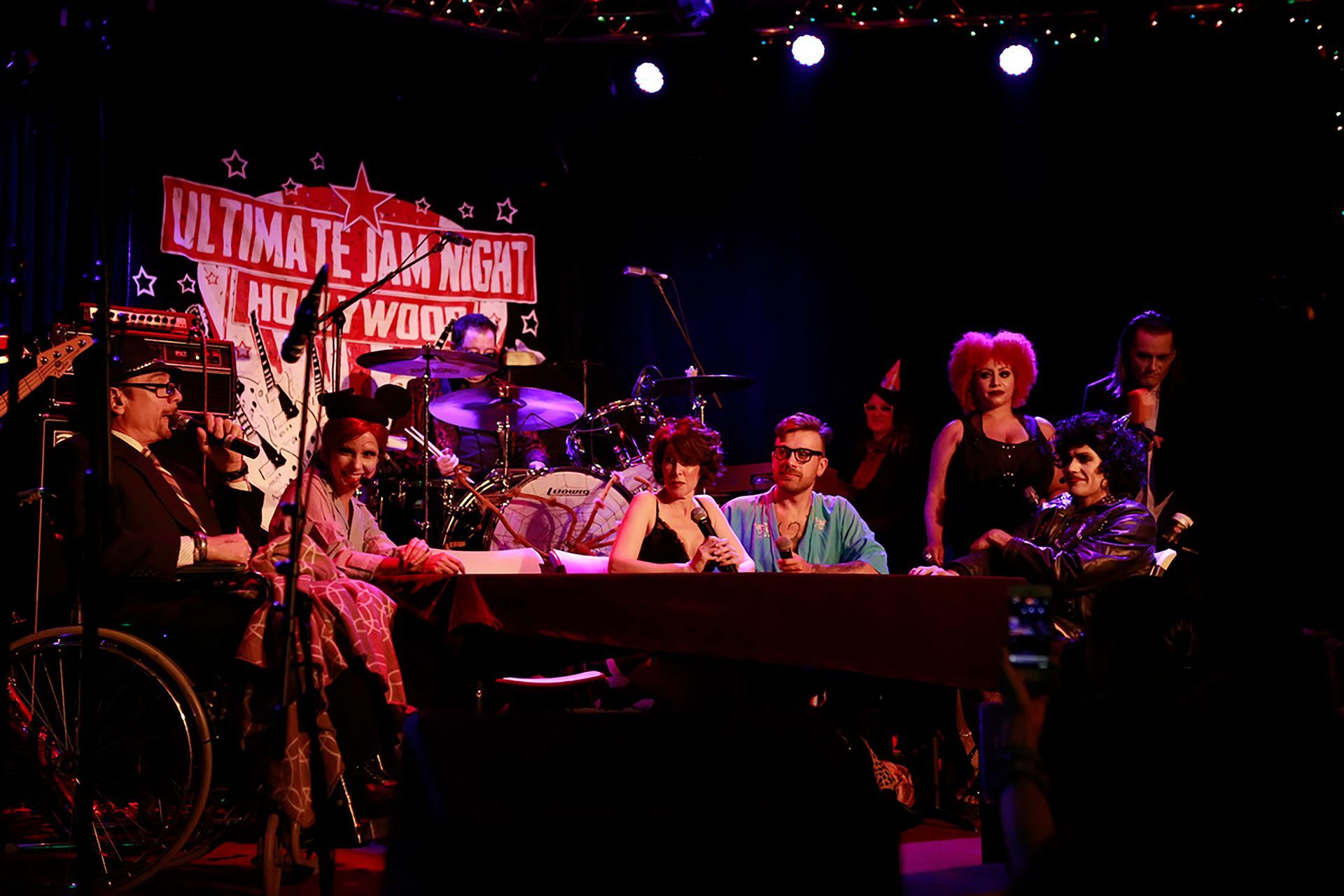 A group of people on a stage with a sign that says ultimate jam night