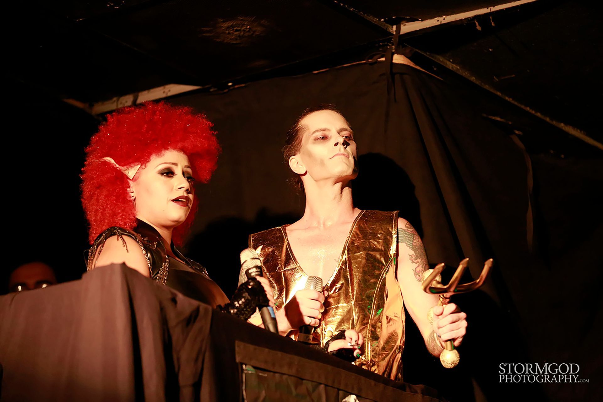 A woman with red hair is standing next to a man holding a trophy