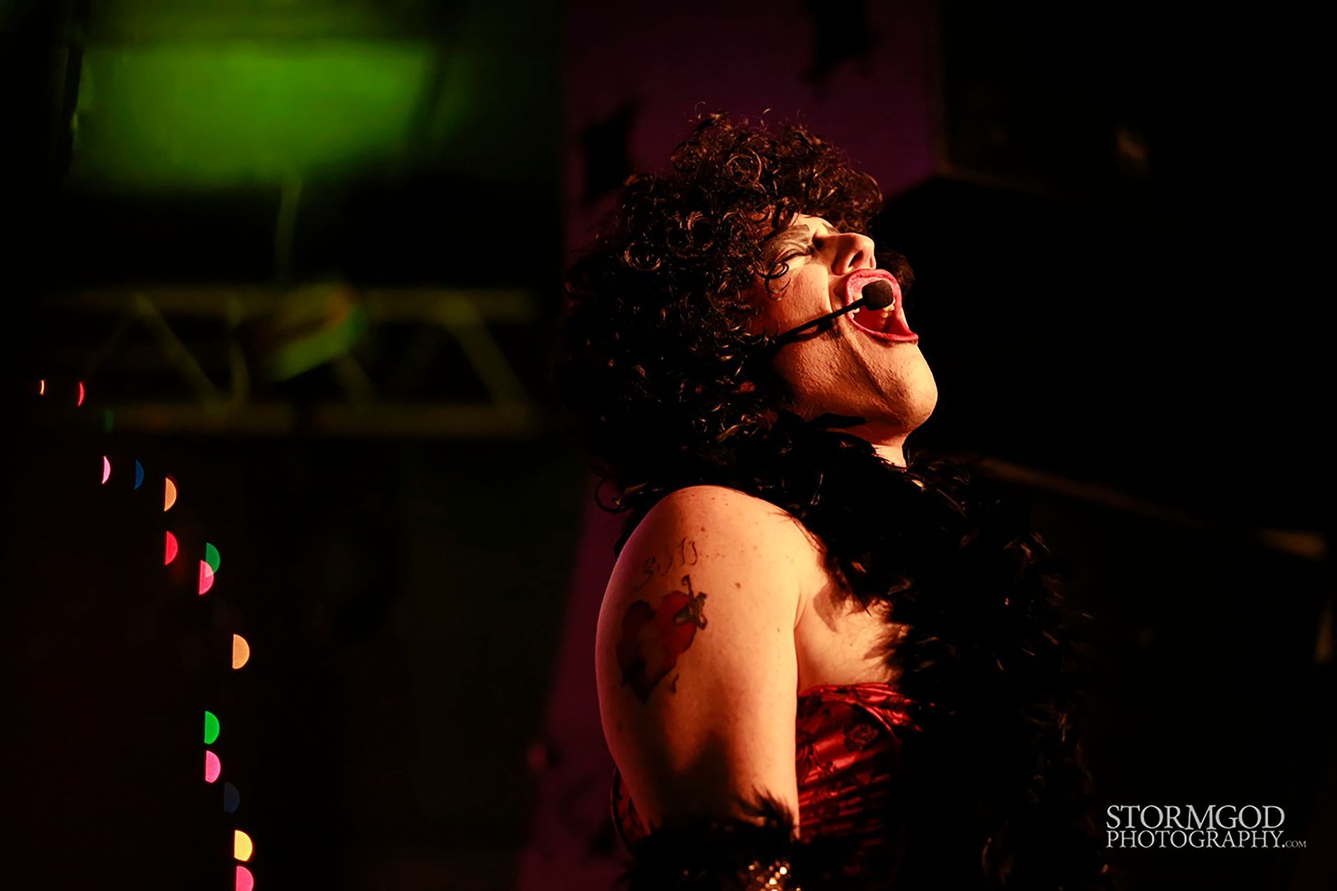 A woman is singing into a microphone in a dark room.