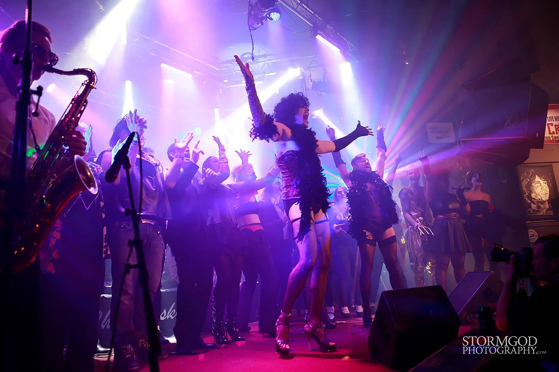 A group of people are dancing on a stage in a dark room.