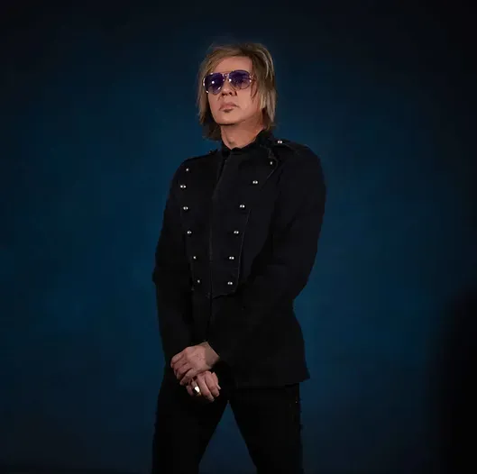 victor bender wearing sunglasses and a black jacket is standing in front of a blue background.