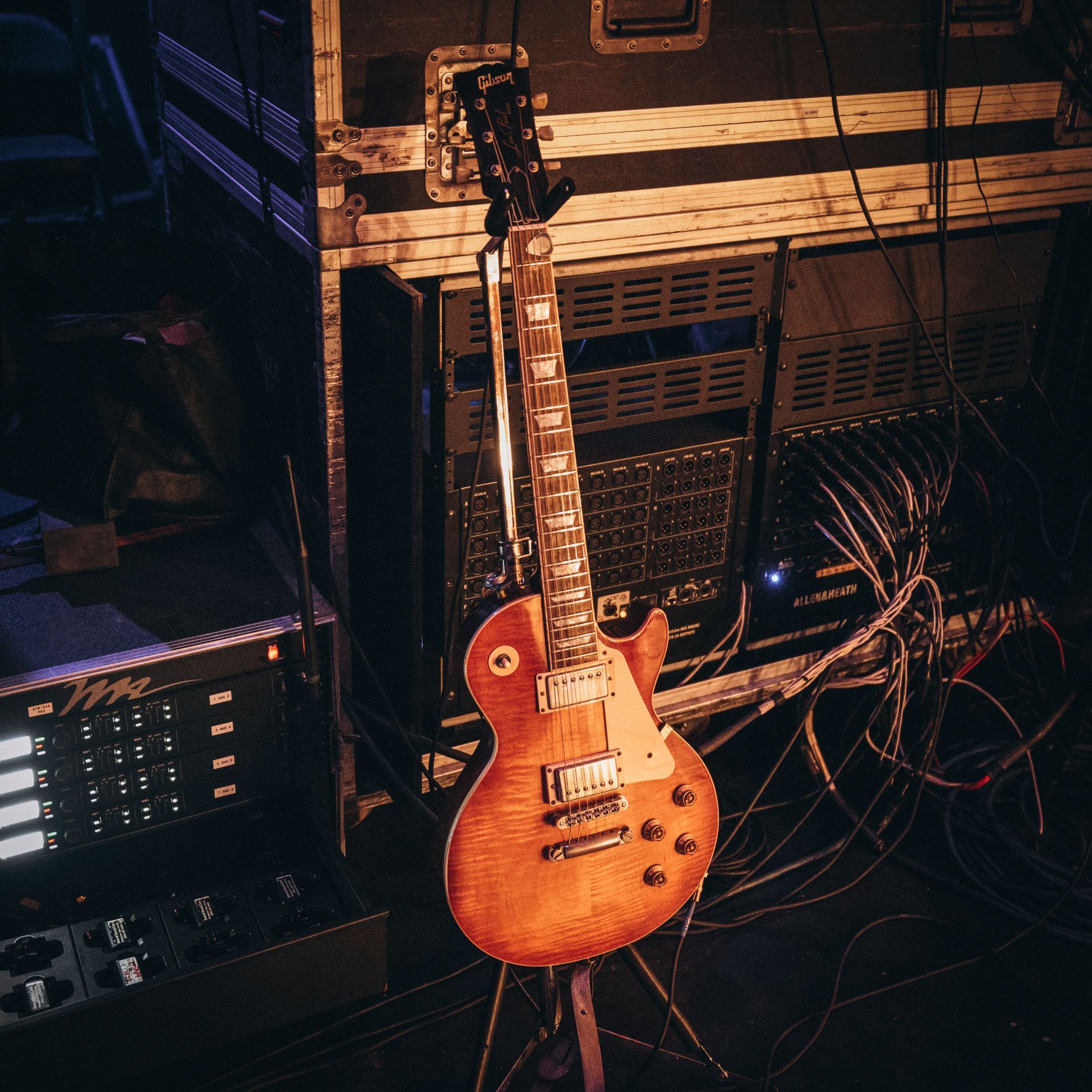 A guitar is sitting on a stand in a dark room