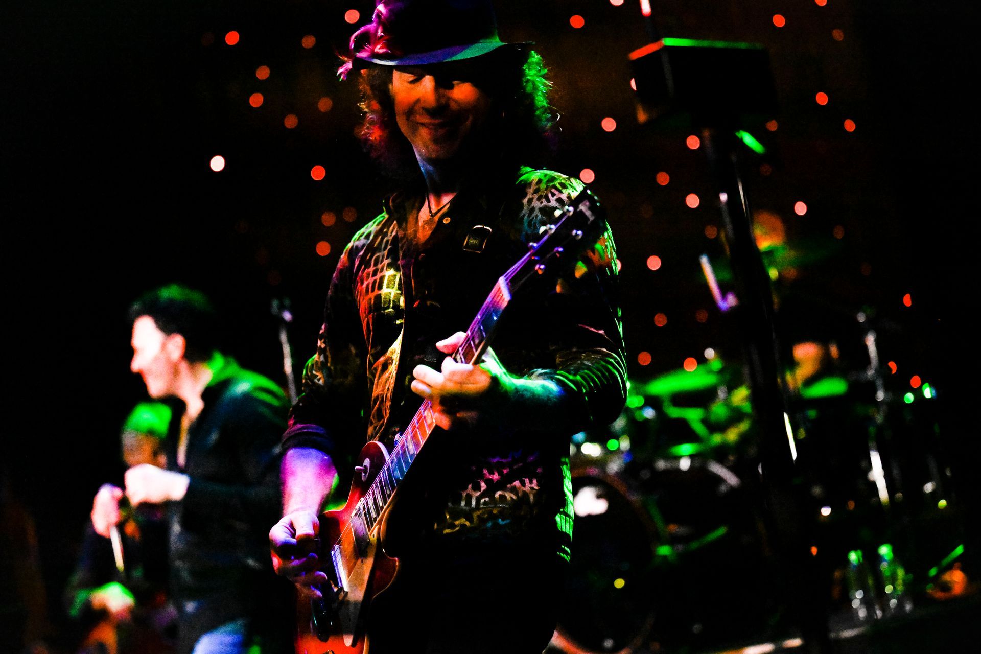 A man in a hat is playing a guitar on stage