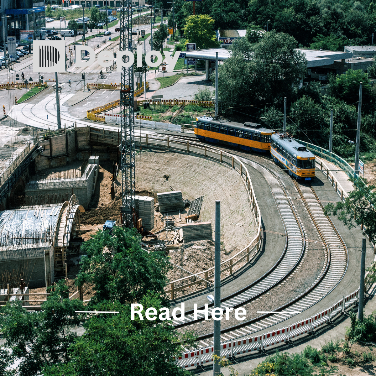 A yellow and blue trolley car on curved tracks, near a construction site and road, in an urban setting.