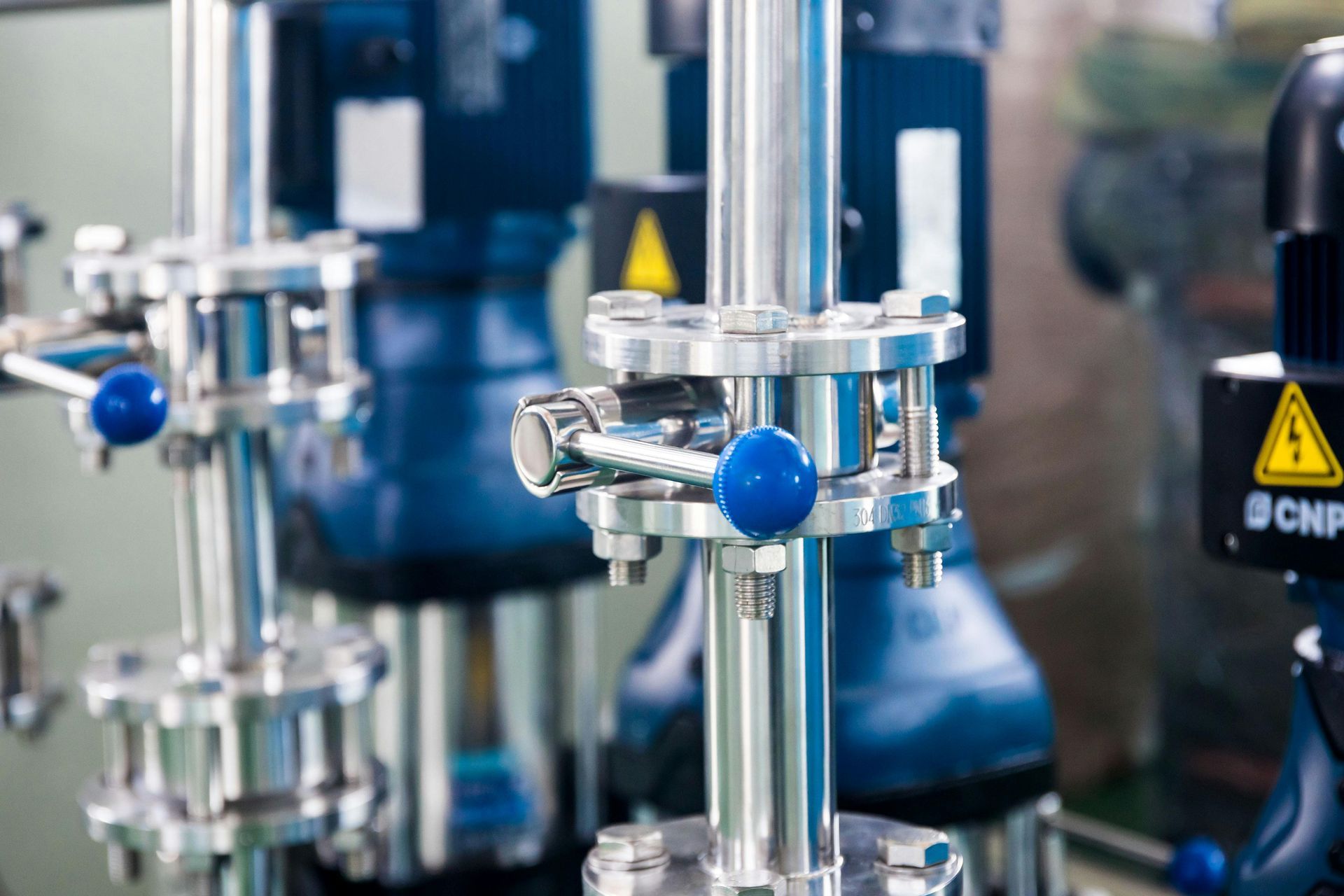 A close up of a machine in a factory with blue valves.